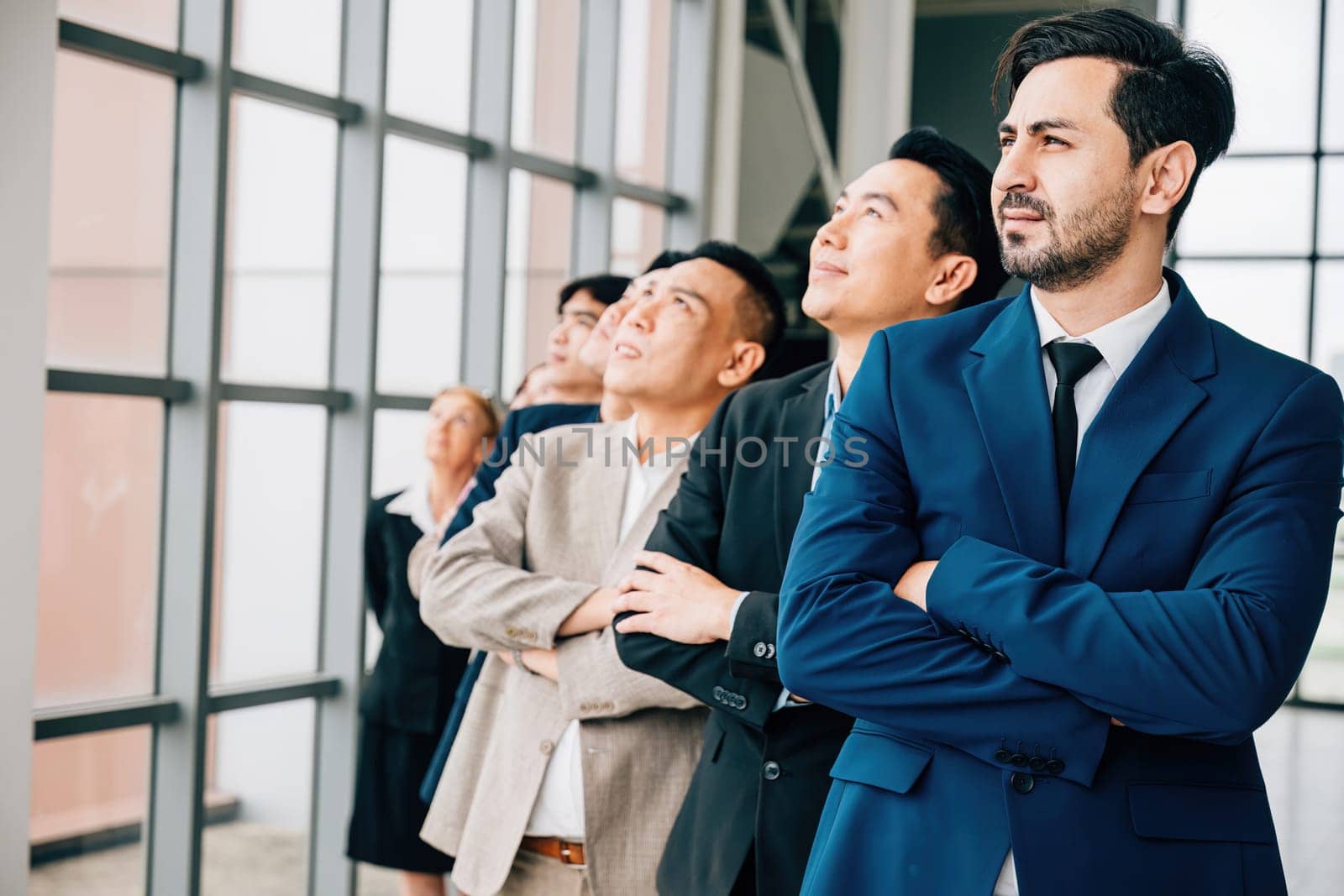 Confidence and success define group portrait of young businesspeople and businessman in office standing with crossed arms. They exemplify strong leadership, teamwork and spirit of a thriving startup. by Sorapop