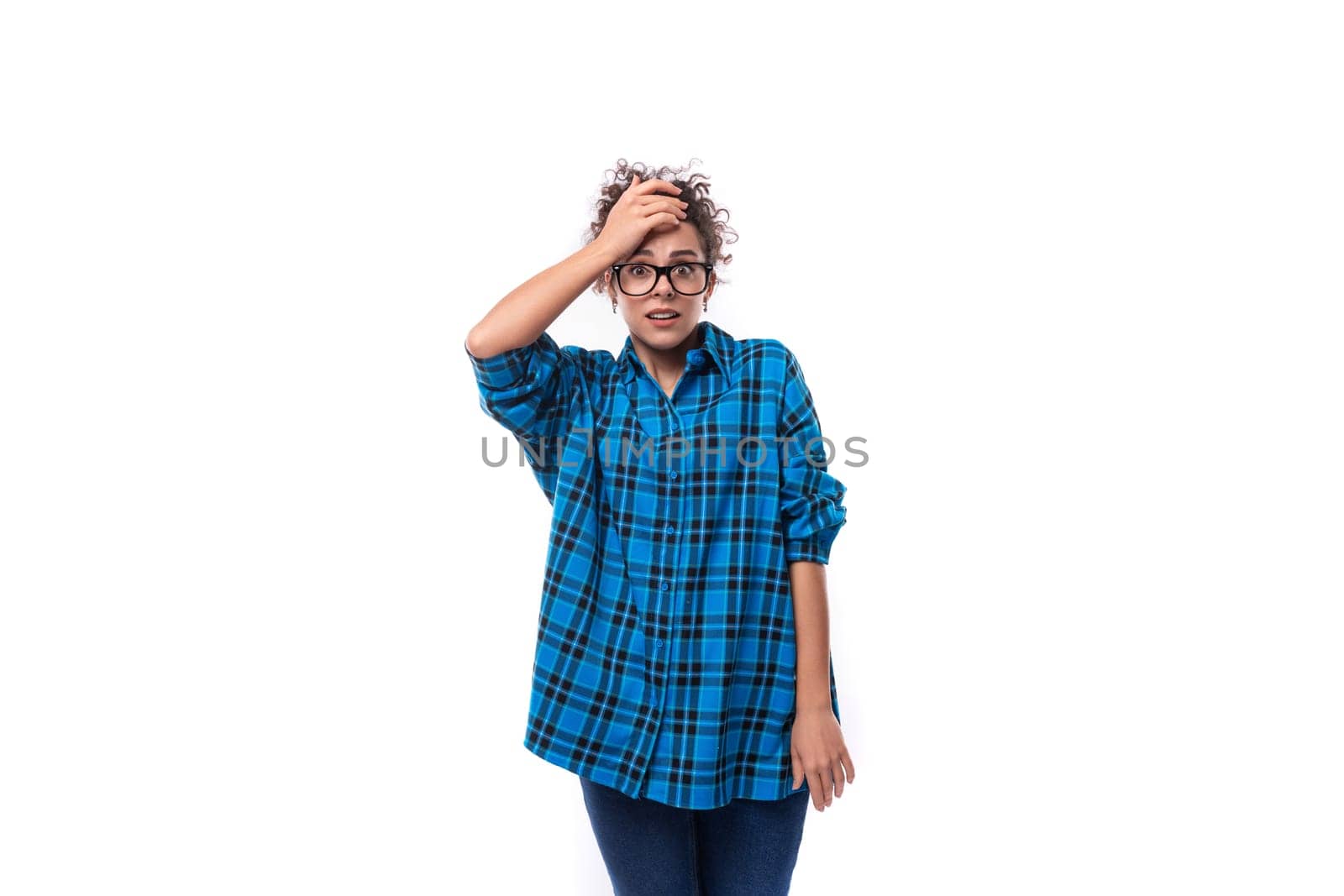a slender young brunette woman in a loose-fitting blue plaid shirt holds her head by TRMK