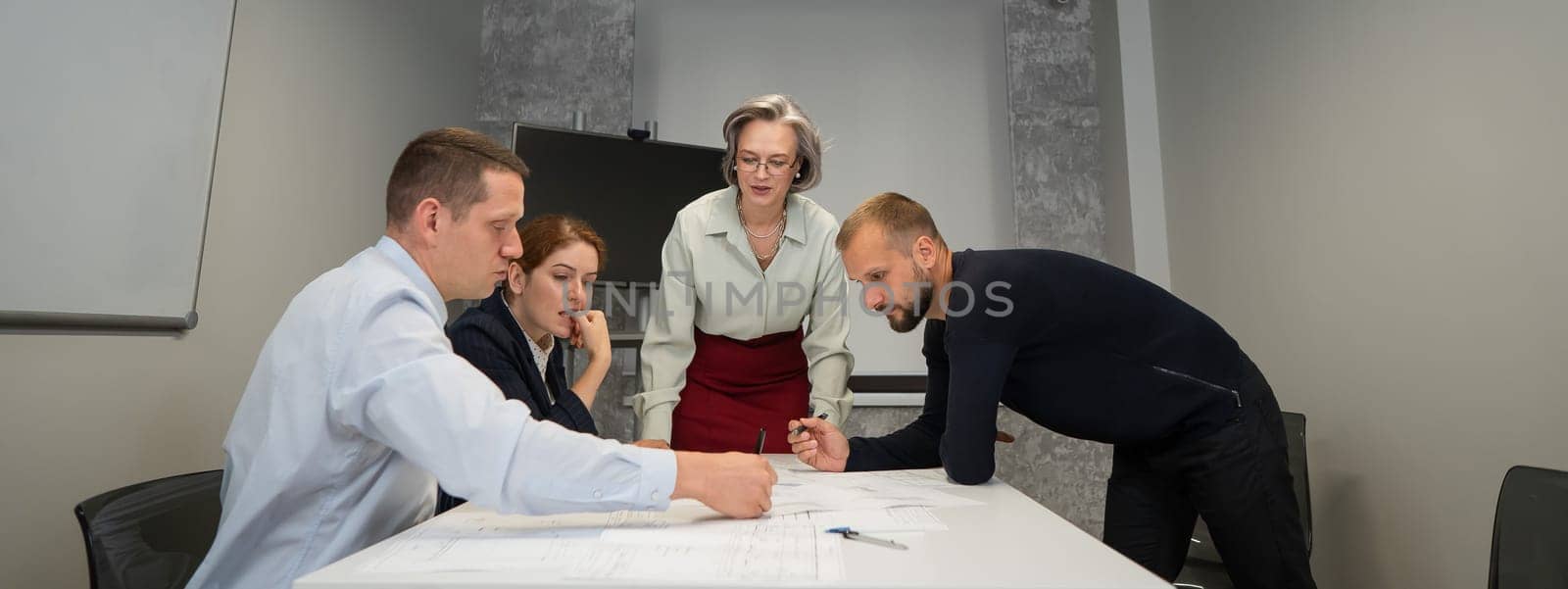 The female boss evaluates the work of subordinates. Designers engineers at a meeting