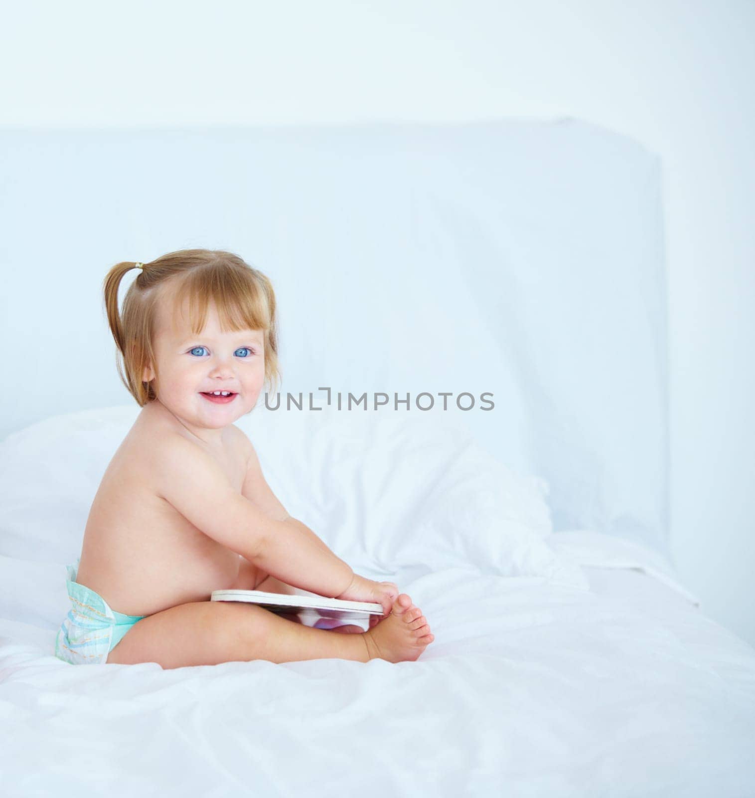 Smile, learning and a baby with a book in the bedroom of a home for growth or child development. Kids, storytelling or reading with a happy young infant girl sitting on a bed in an apartment by YuriArcurs