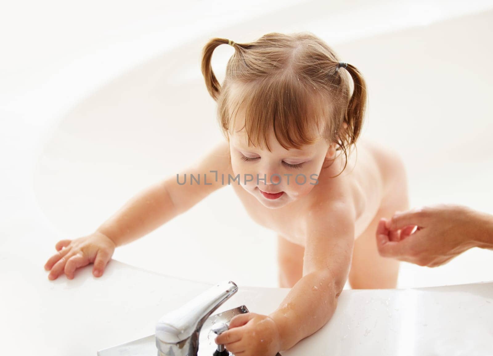 Kids, cleaning and water with a baby in the bath for natural skincare, development or hygiene. Children, bathroom and a curious young toddler girl in a bathtub for health and wellness in her home by YuriArcurs