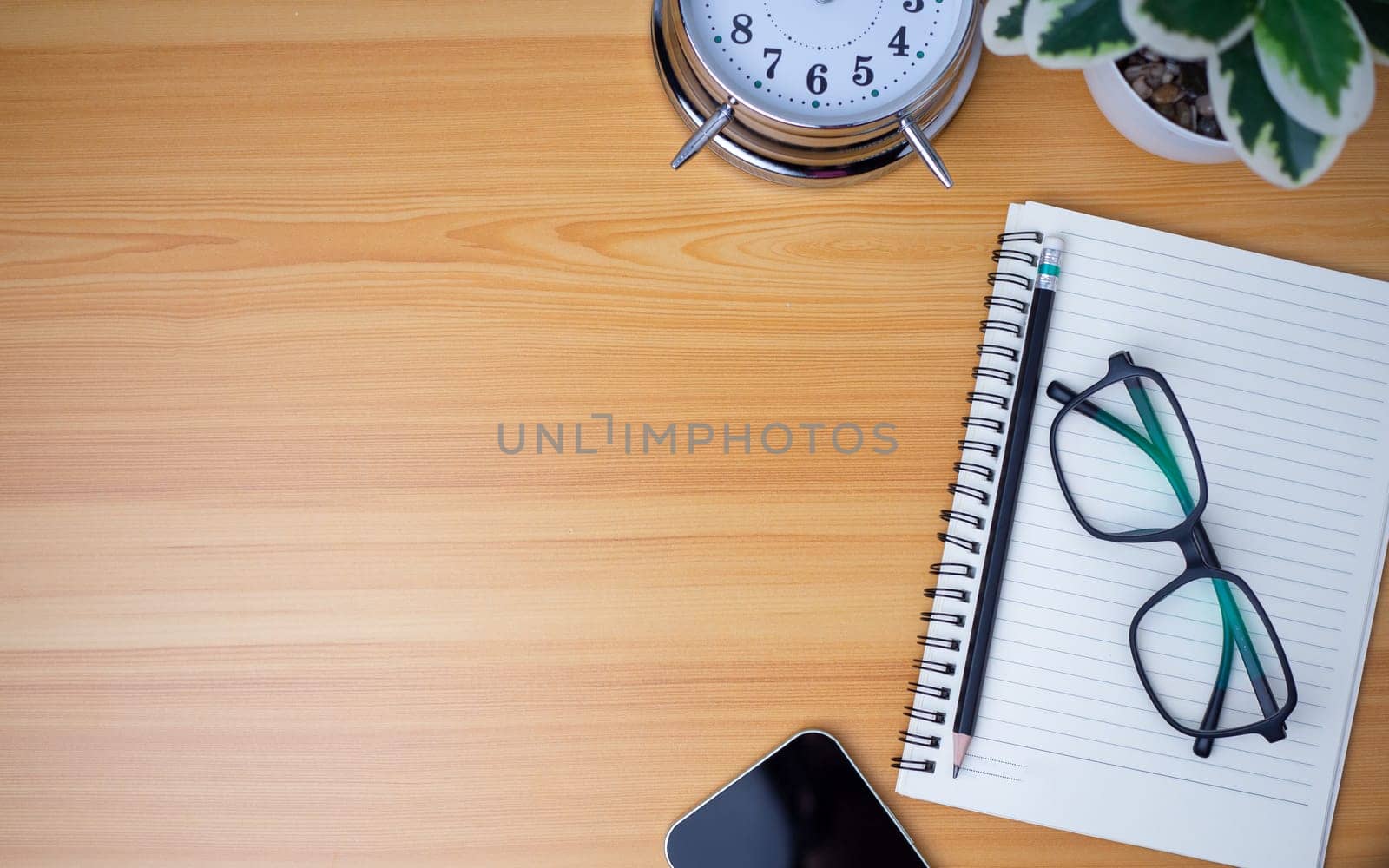 Office table of modern workplace with notebooks and pencils, phone, clock on wooden table. Top view and copy space on wooden floor, Flat lay, top view office table with glasses.