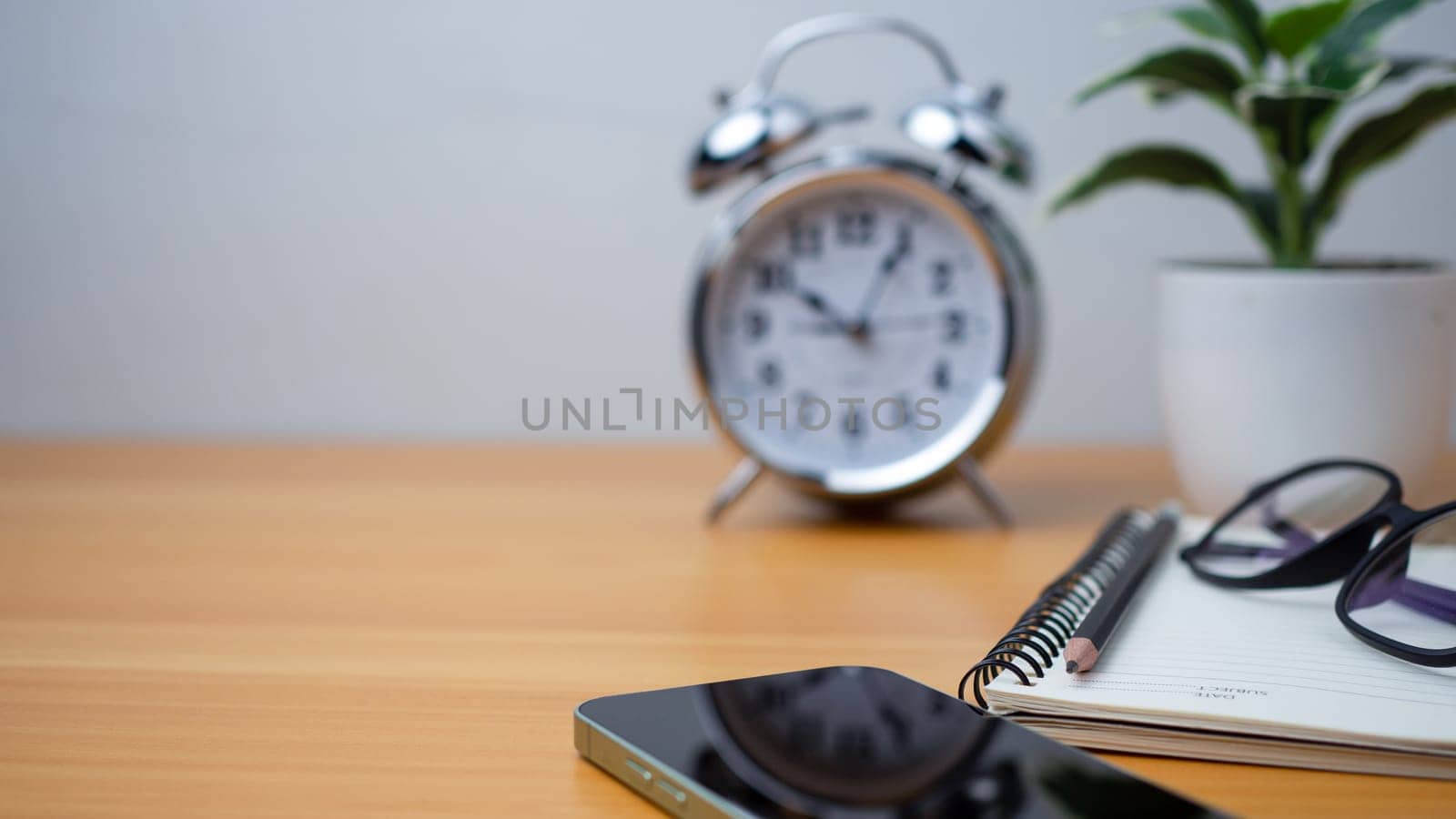 Office table of modern workplace with notebooks and pencils, phone, clock on wooden table. side view and copy space on wooden floor, Flat lay, side view office table with glasses.