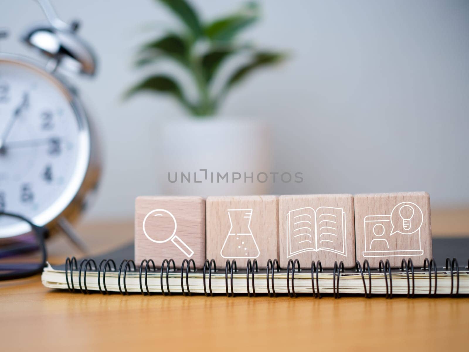 Educational concept Creativity and innovation Square wooden blocks are arranged together with educational icons on top of a notebook. by Unimages2527