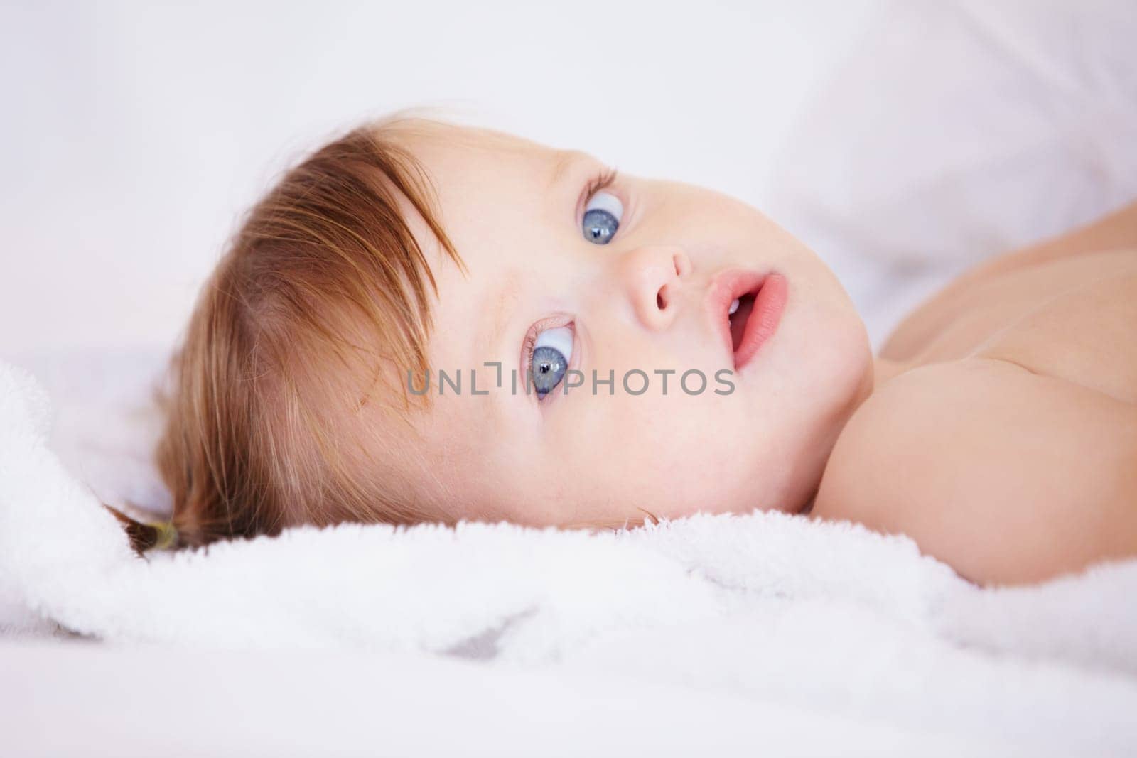 Portrait, growth and child development with a baby in the bedroom to relax alone in the morning. Face, kids or youth and an adorable young infant girl on a bed with blankets for comfort in a home by YuriArcurs