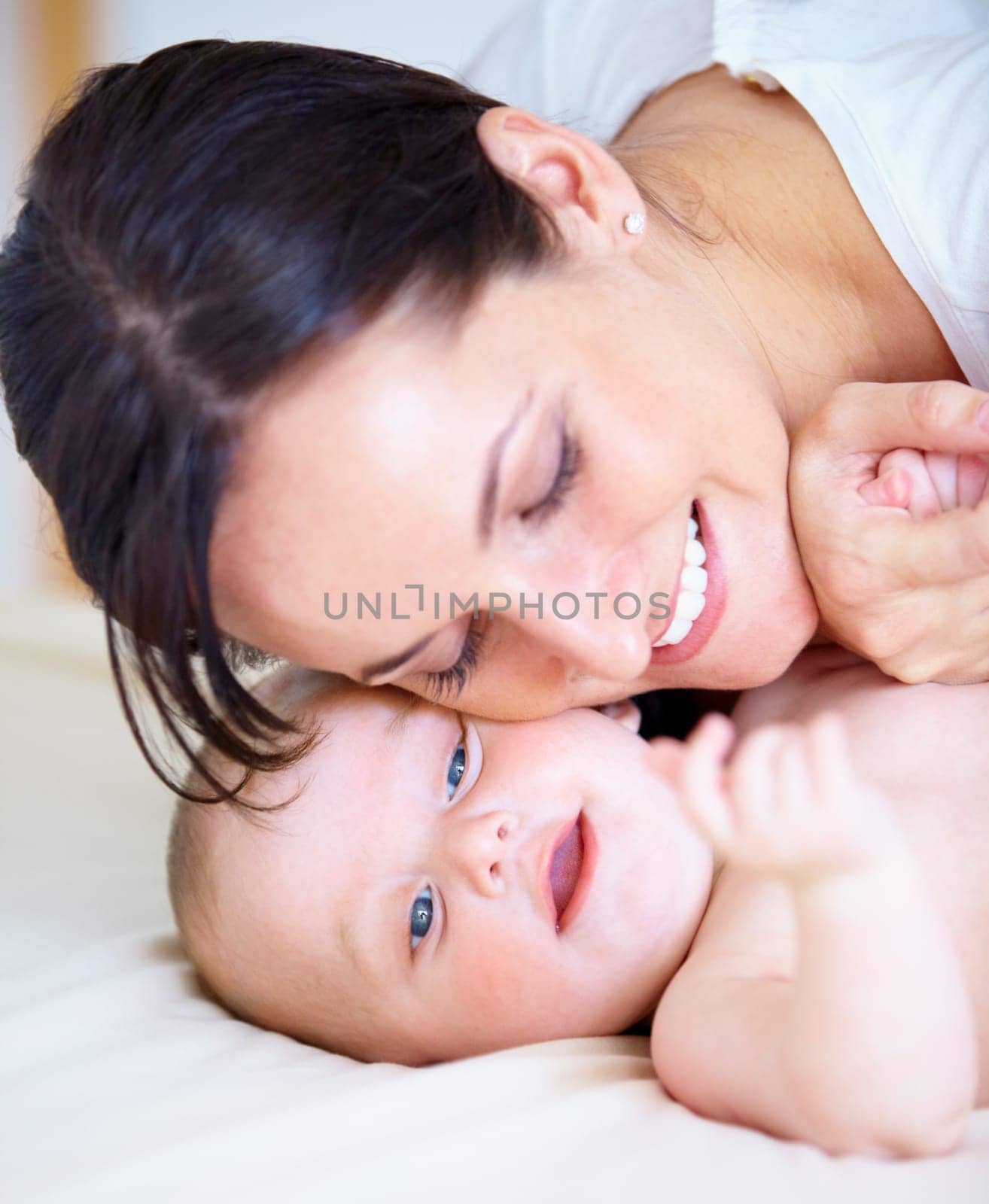 Face, family or love with a mother and baby closeup on a bed in their home together for bonding. Growth, smile or happy with a young woman parent and infant child in the bedroom of an apartment by YuriArcurs