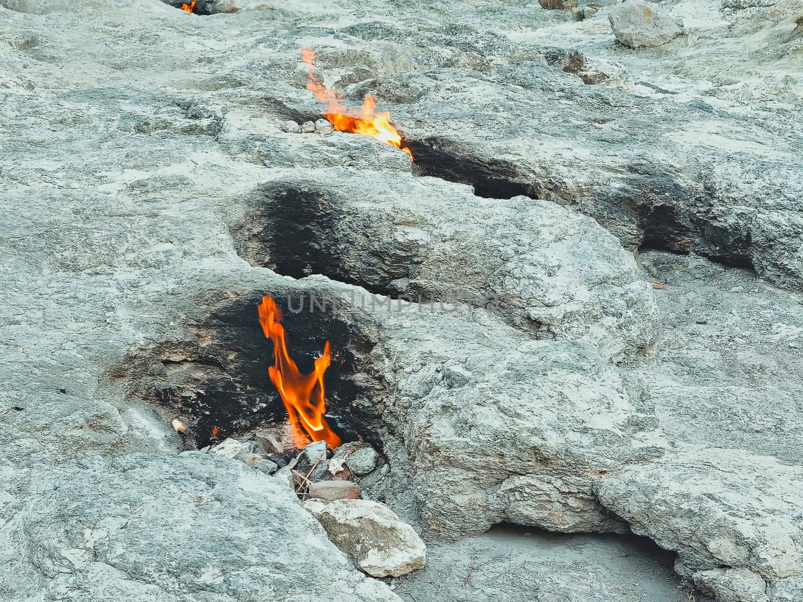 fire from mountain, stones are burning, flame of Chimera shoots out from under ground. Natural gas fire in rocks in Cirali, Turkey. by Leoschka