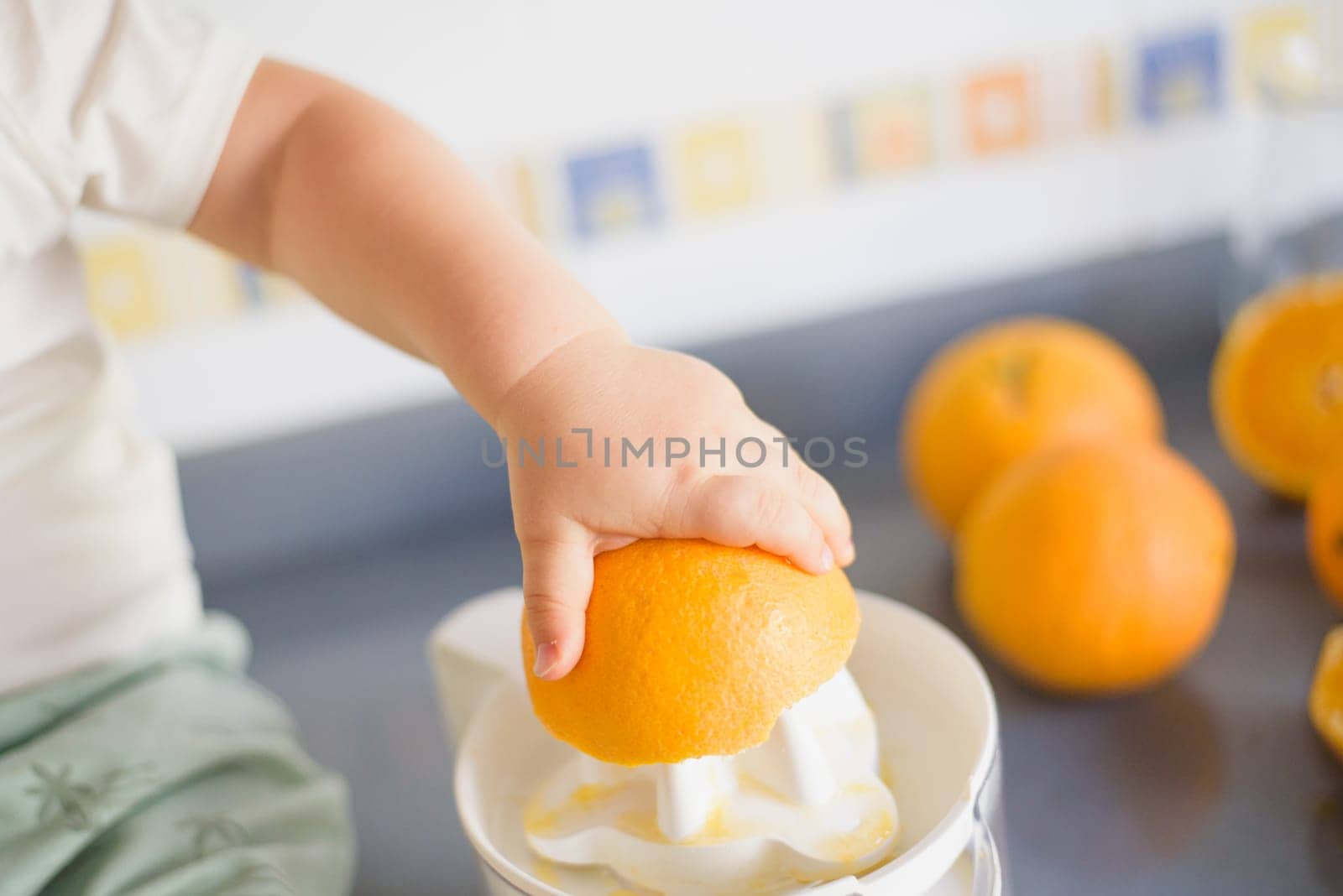 a girl child makes freshly squeezed orange juice on a manual juicer.