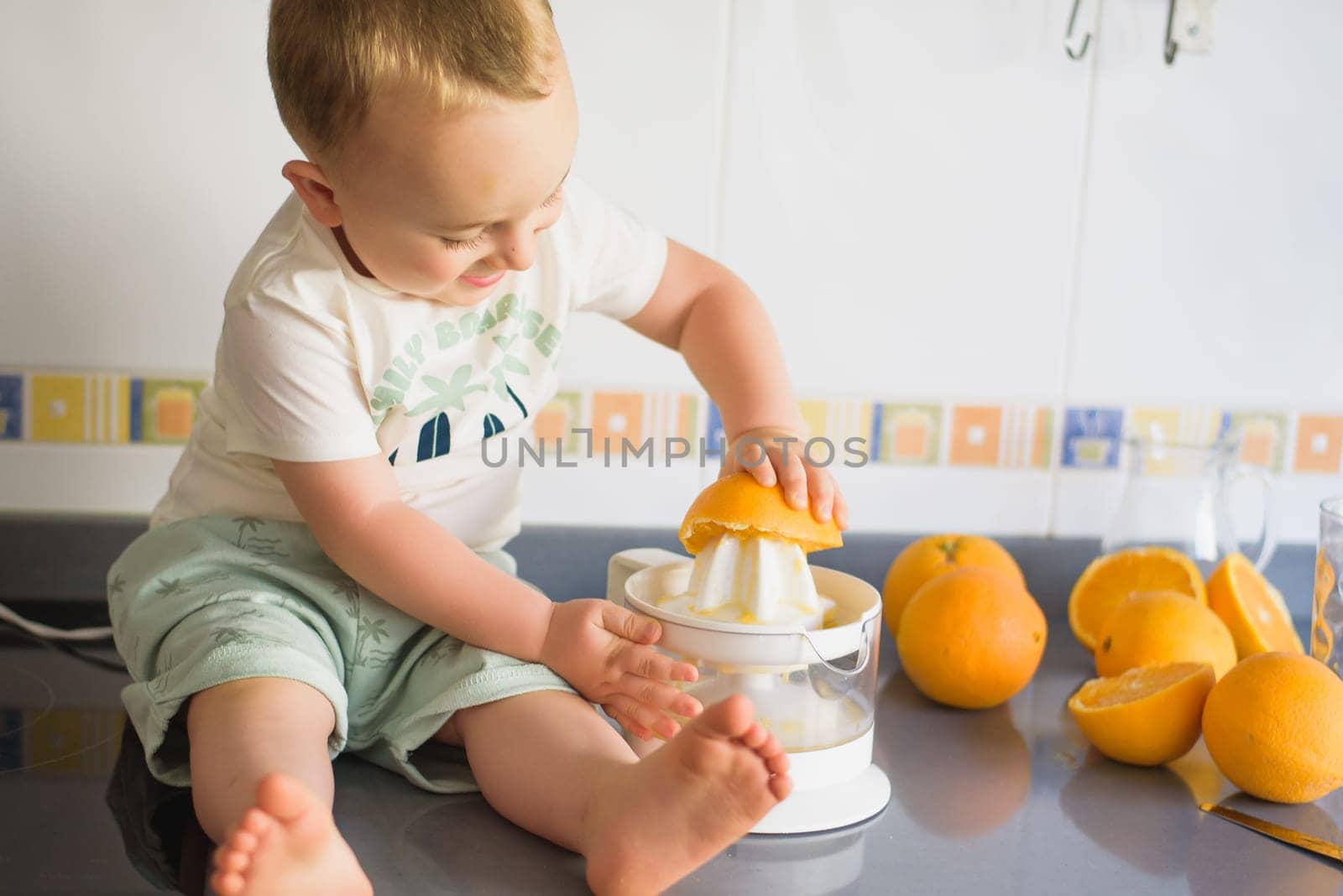 a boy child makes freshly squeezed orange juice on a manual juicer by jcdiazhidalgo