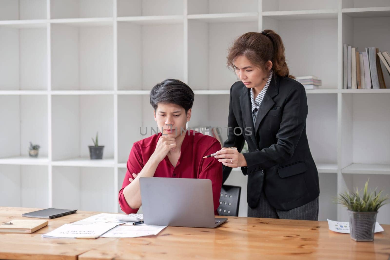 Two businessmen are stressed while explaining workflow on laptop to colleague. by wichayada