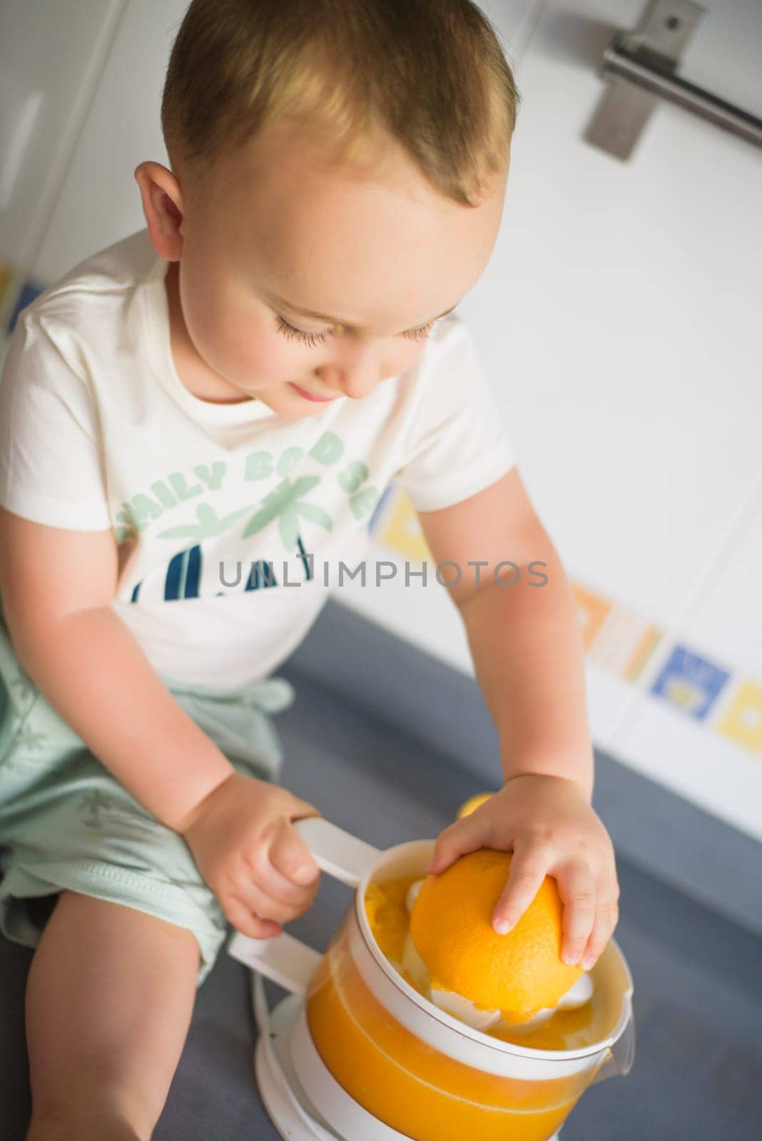 a girl child makes freshly squeezed orange juice on a manual juicer.