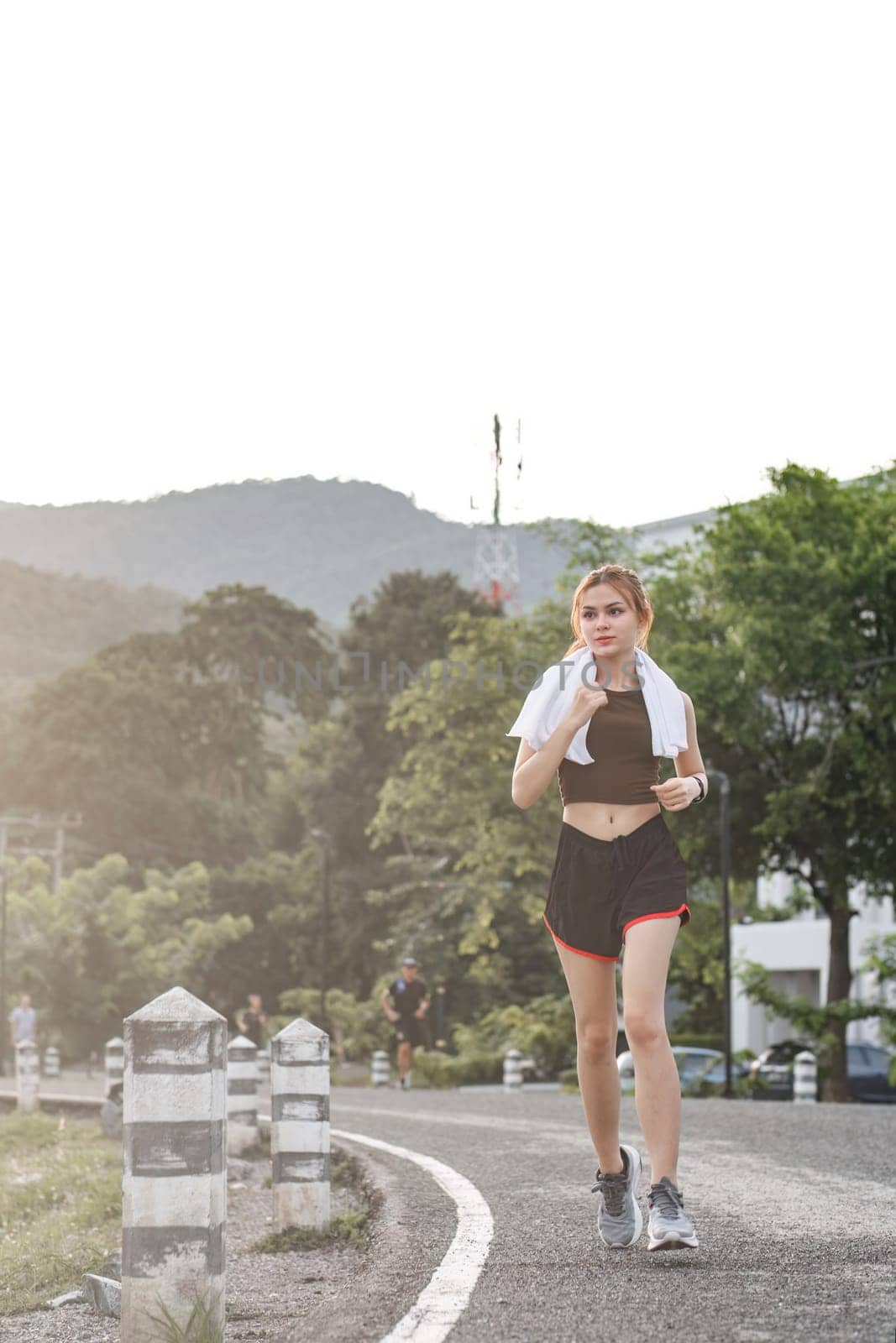 Young sporty woman jogging in the green park in the evening by wichayada