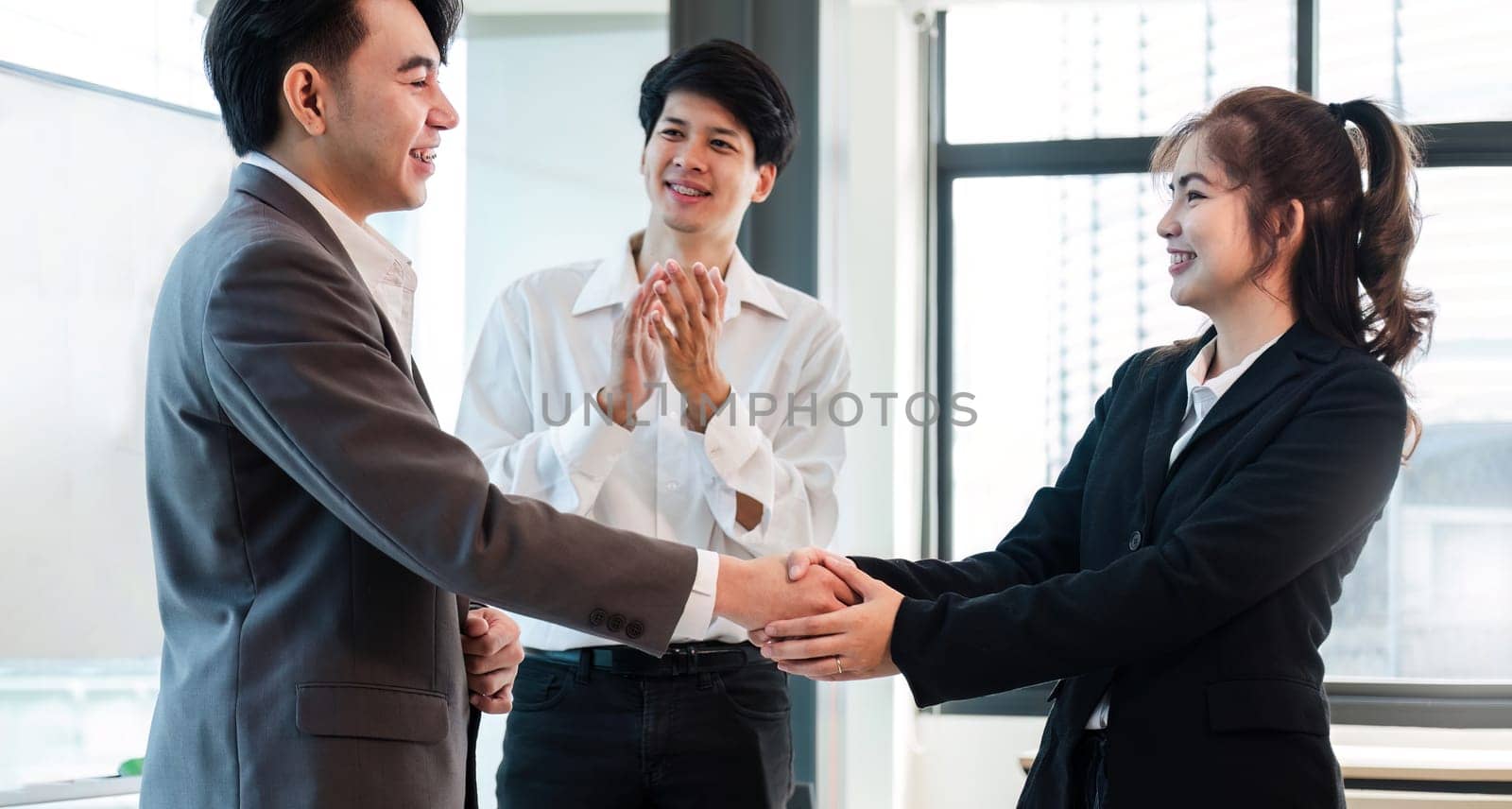 Young business people shaking hands in the office. Finishing successful meeting. by wichayada