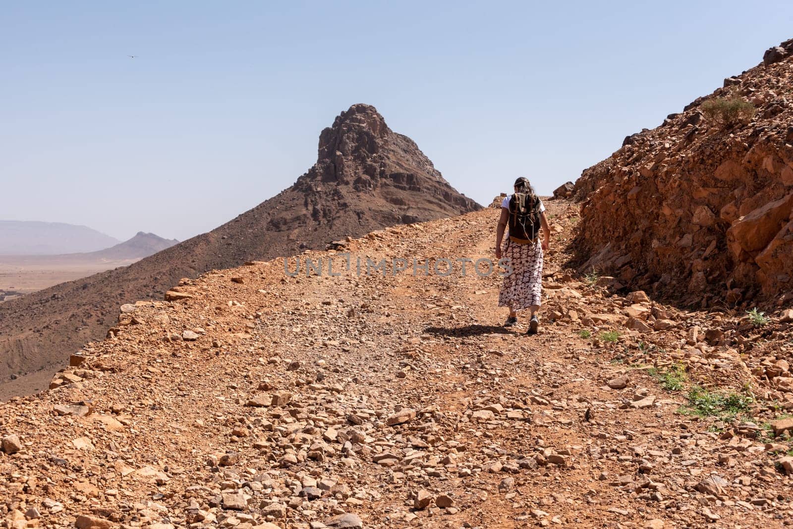 Hiking up the mount Zagora on a gravel road, mount Adafane in the background, Draa valley in Morocco