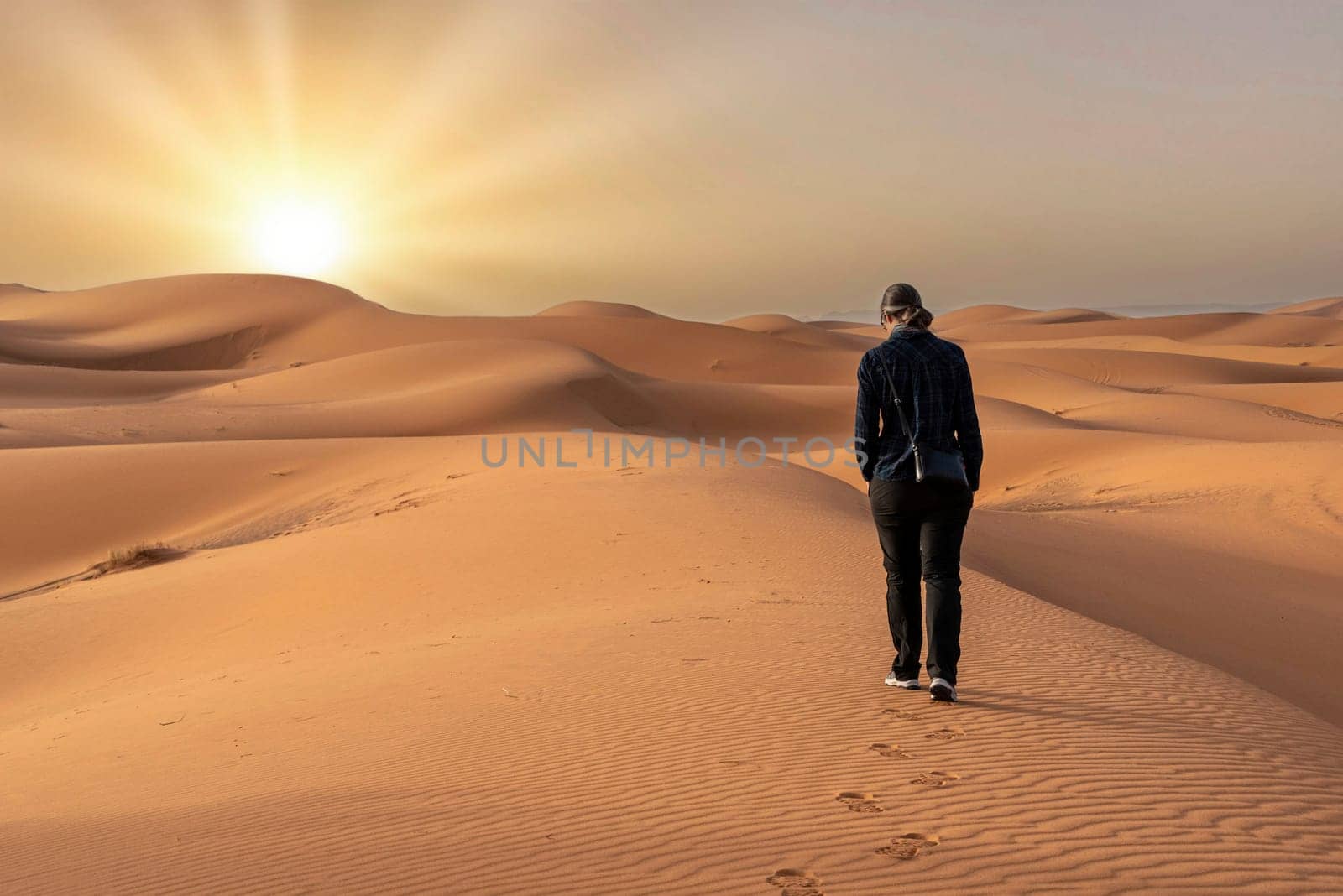 A person walking through the Erg Chebbi desert in the African Sahara, Morocco