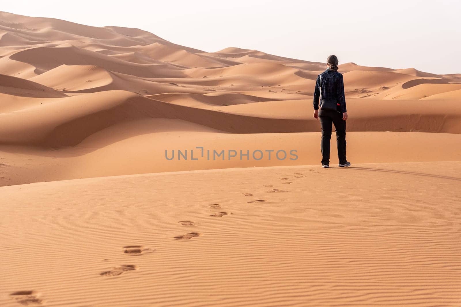 A person walking through the Erg Chebbi desert in the African Sahara, Morocco