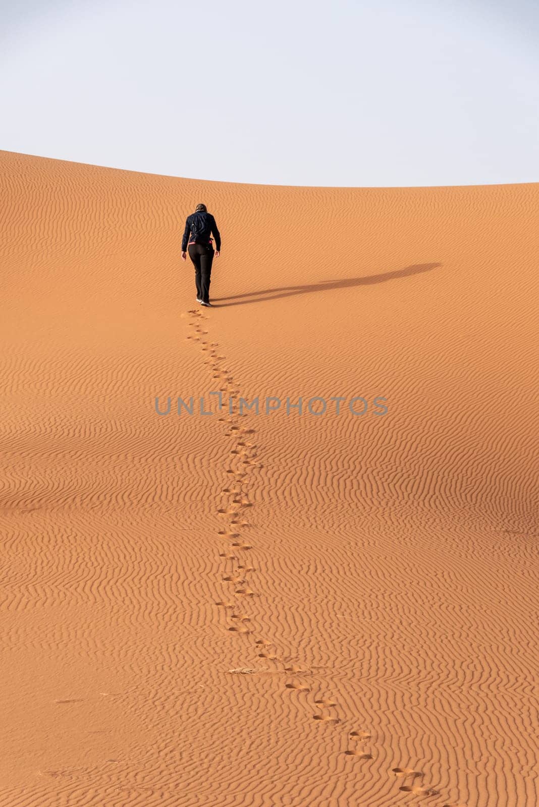 A person walking through the Erg Chebbi desert in the African Sahara, Morocco