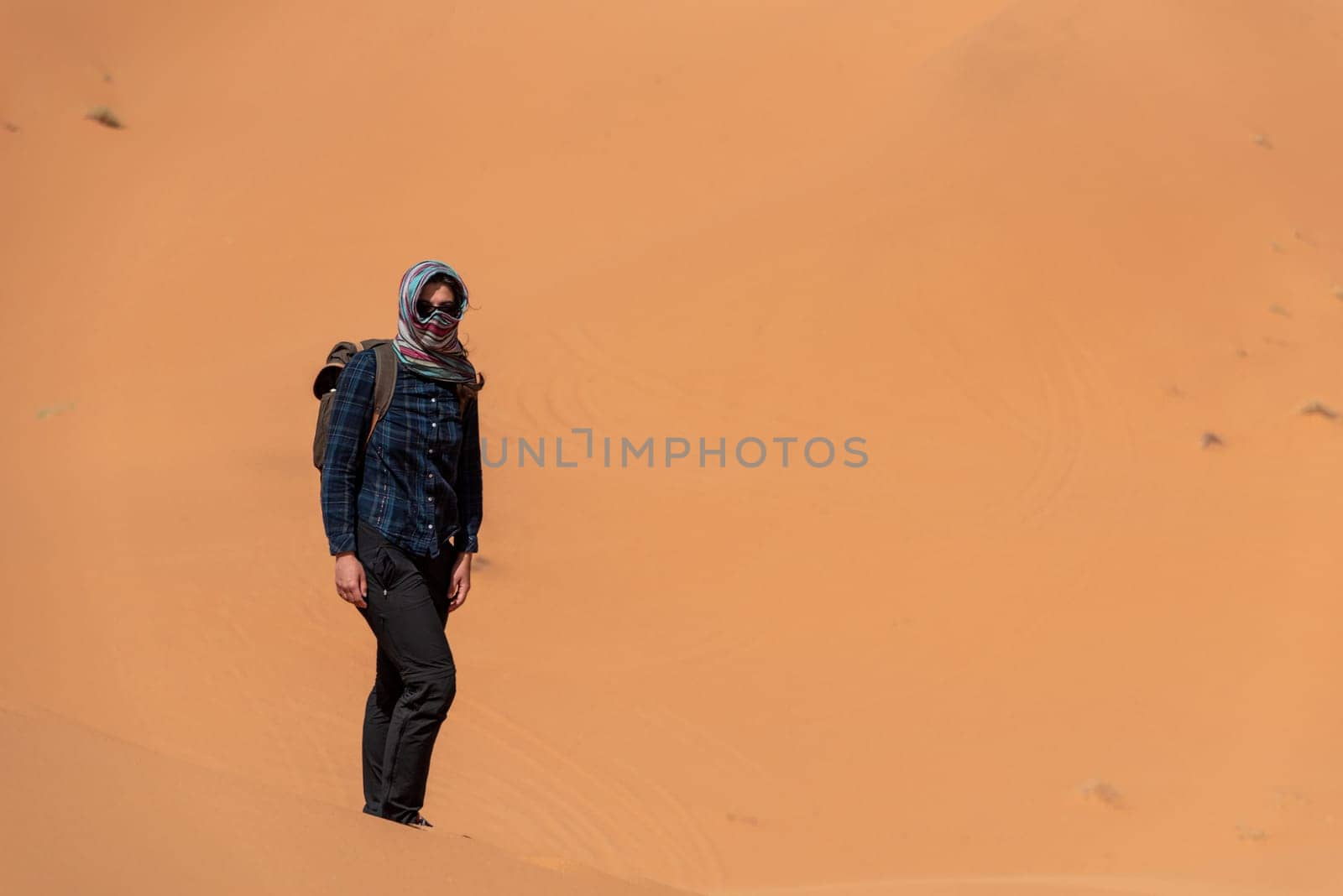A person walking through the Erg Chebbi desert in the African Sahara by imagoDens