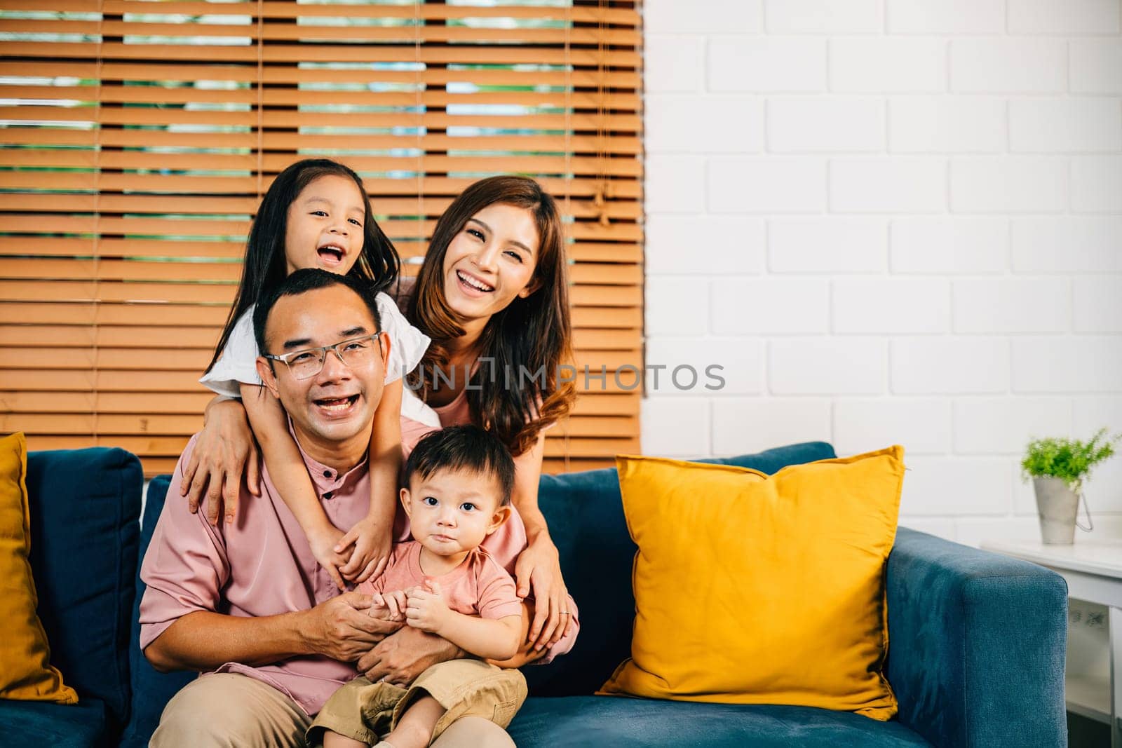A joyful family in their comfortable modern house enjoys quality time on the sofa by Sorapop