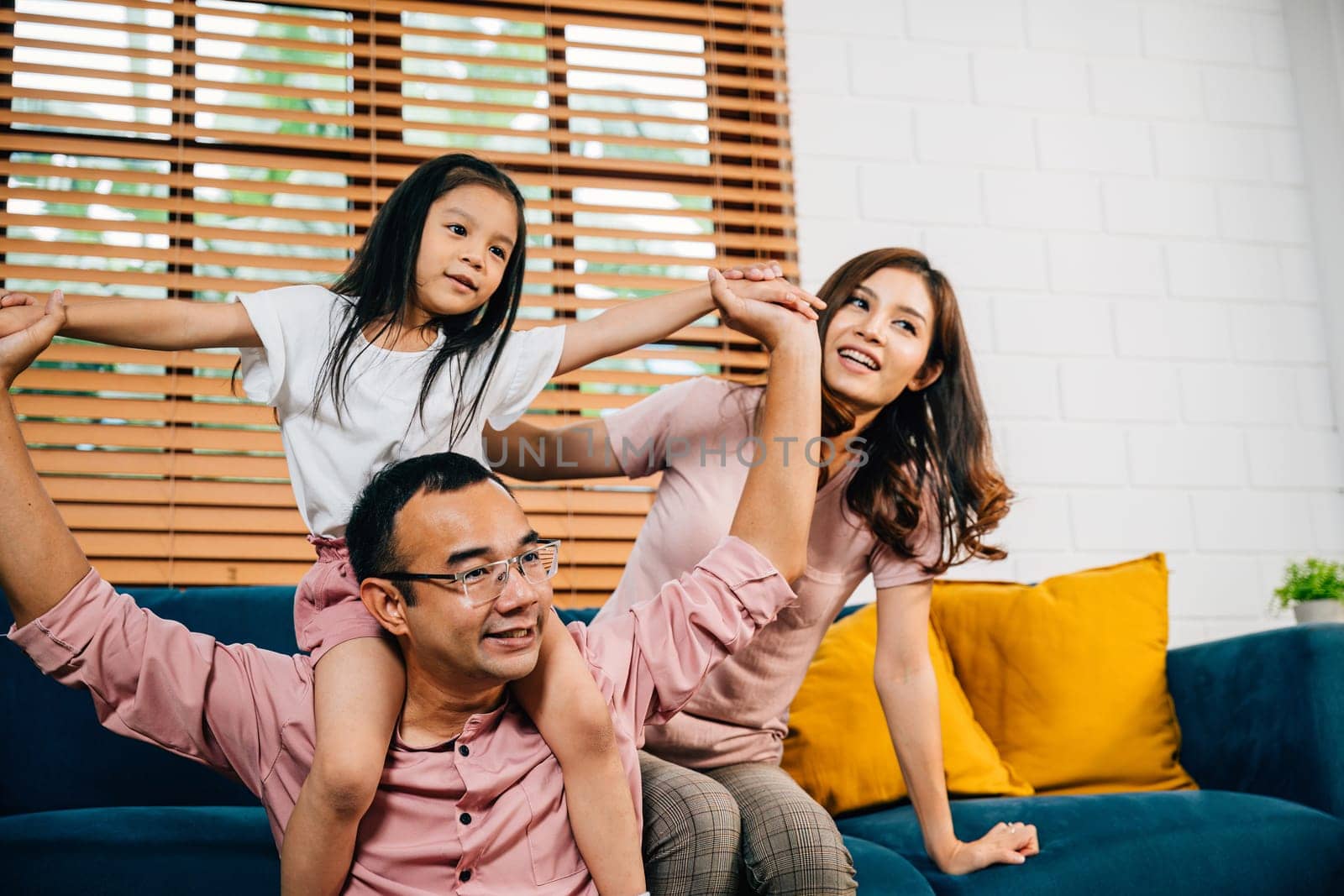 A joyful family in their comfortable modern house enjoys quality time on the sofa by Sorapop