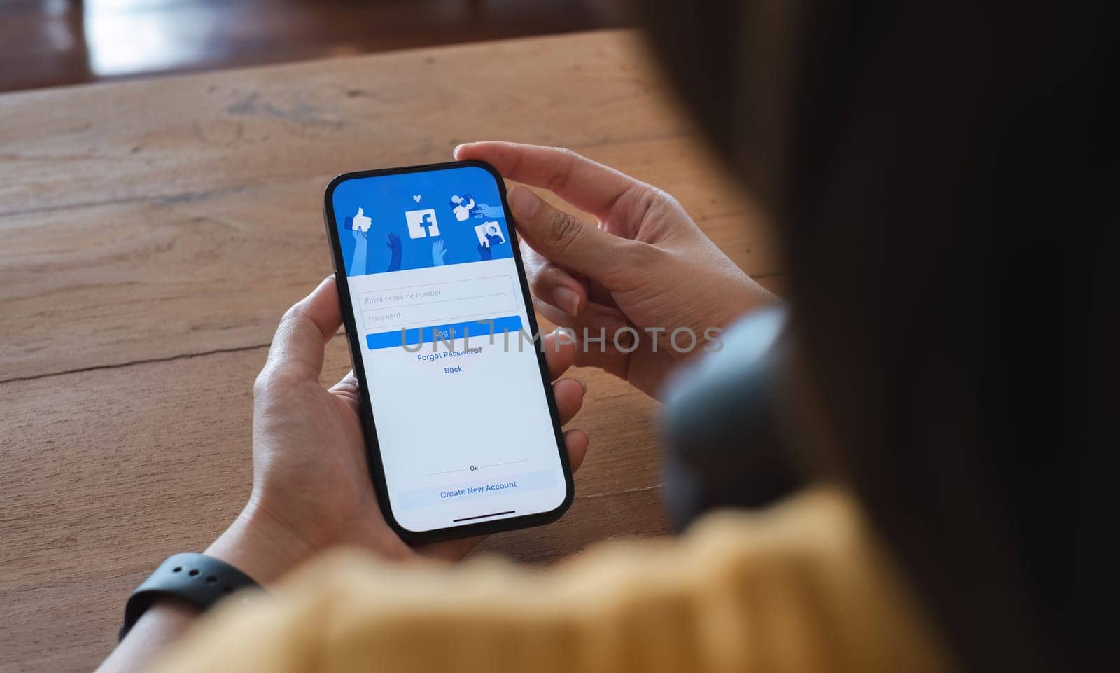 CHIANG MAI ,THAILAND - NOV 16, 2023 : Woman hand holding iPhone 14 to use facebook with new login screen.Facebook is a largest social network and most popular social networking site in the world. by wichayada