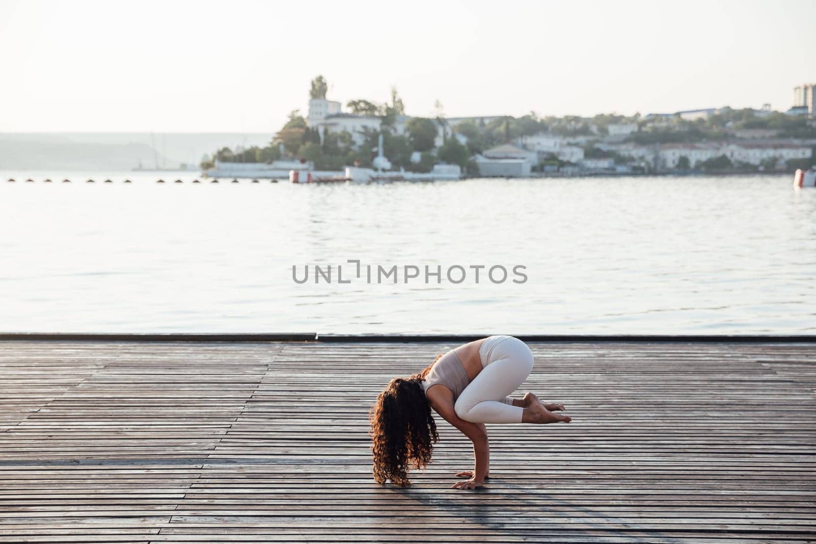 Full length portrait of a middle aged woman doing yoga or pilates on a mat outside in a park.