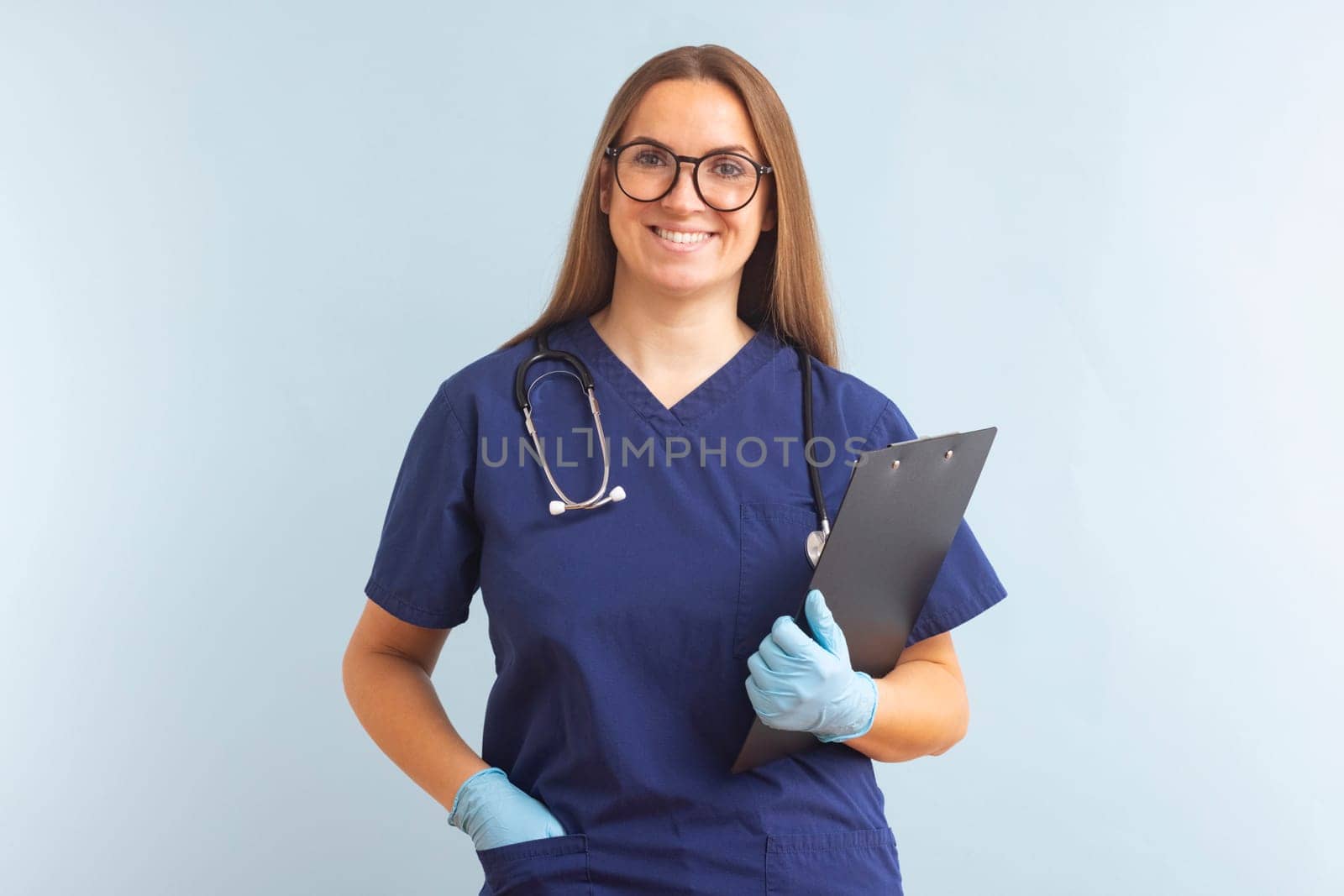 Portrait of smiling woman doctor posing and smiling at camera on blue background by andreyz
