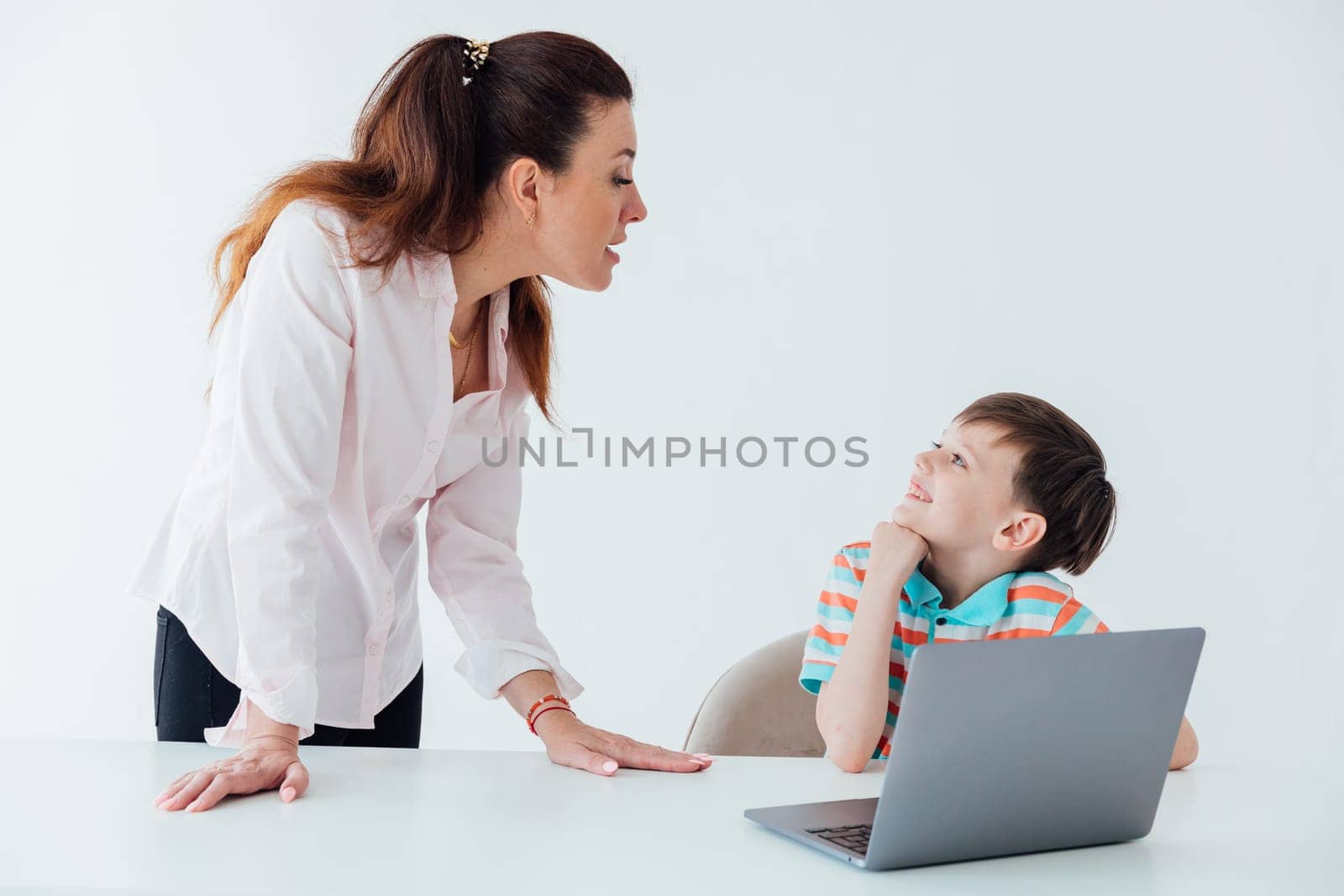 Woman with boy watching online laptop at table