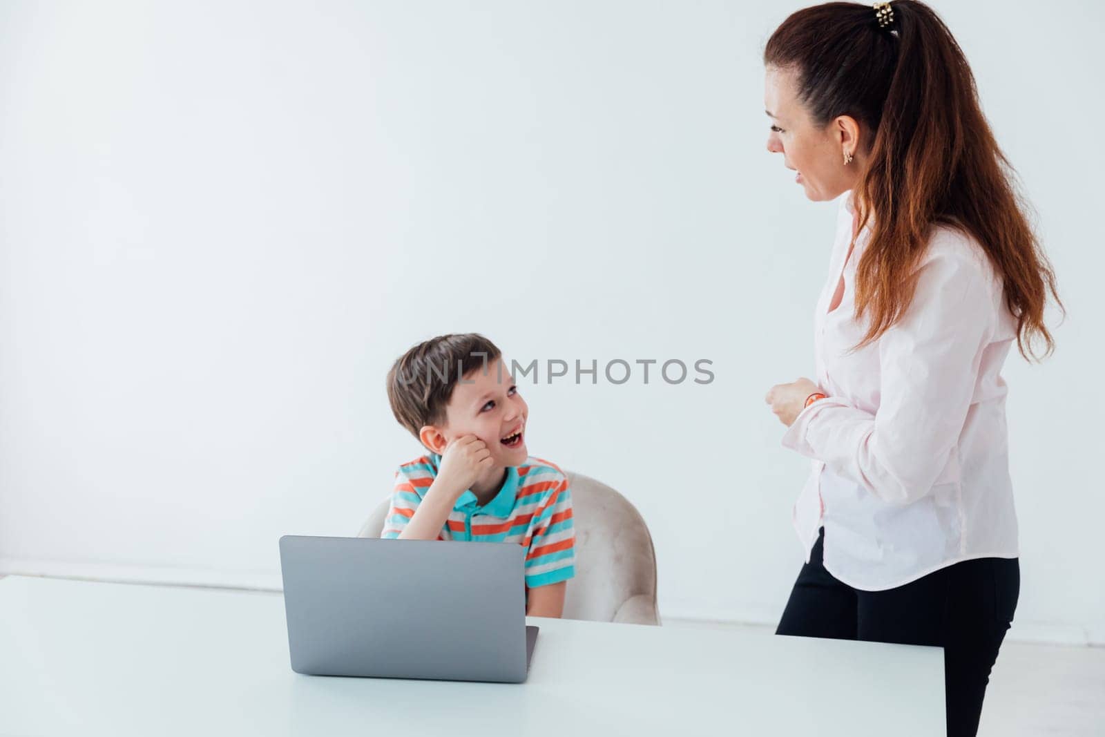 Woman teaching boy on laptop in school