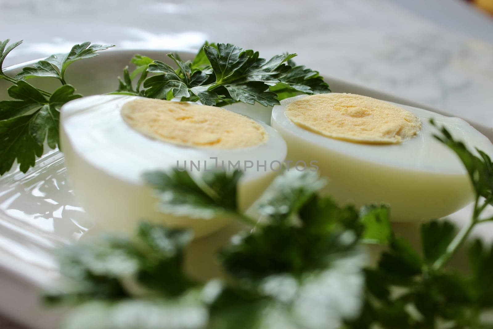 Boiled chicken egg and parsley on a white plate on a marble background. High quality photo