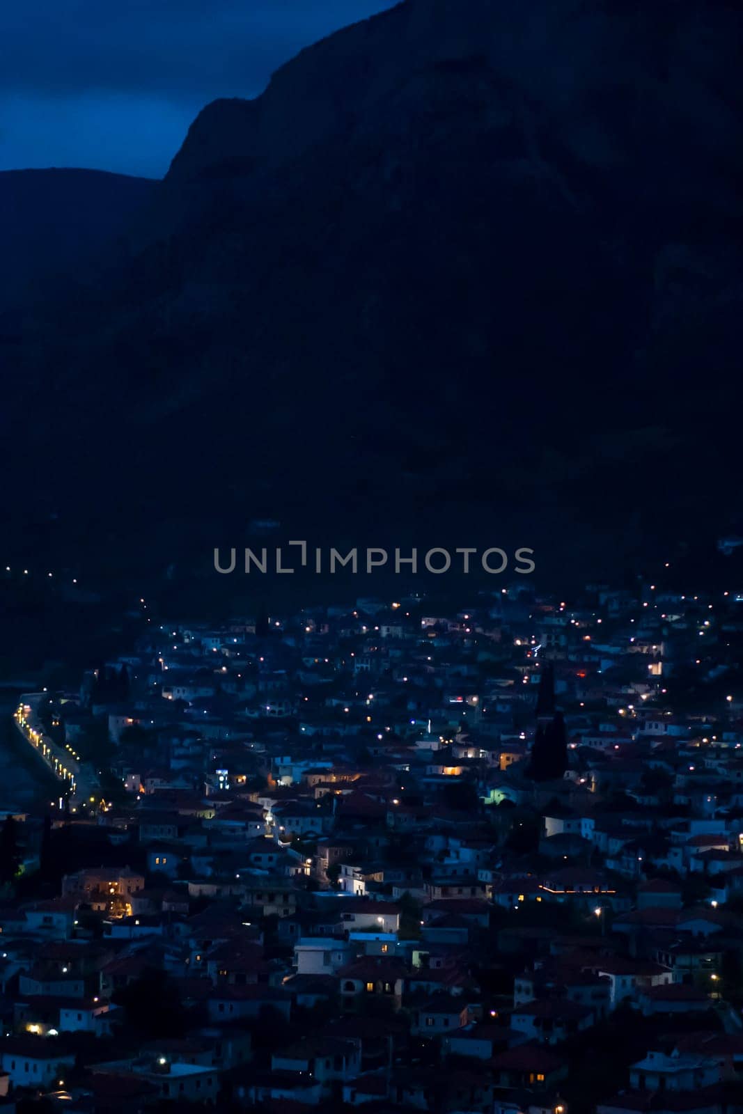 View of a small village among the mountains with street lights illuminated by lanterns late at night, in the dark, a scenic beautiful cityscape.