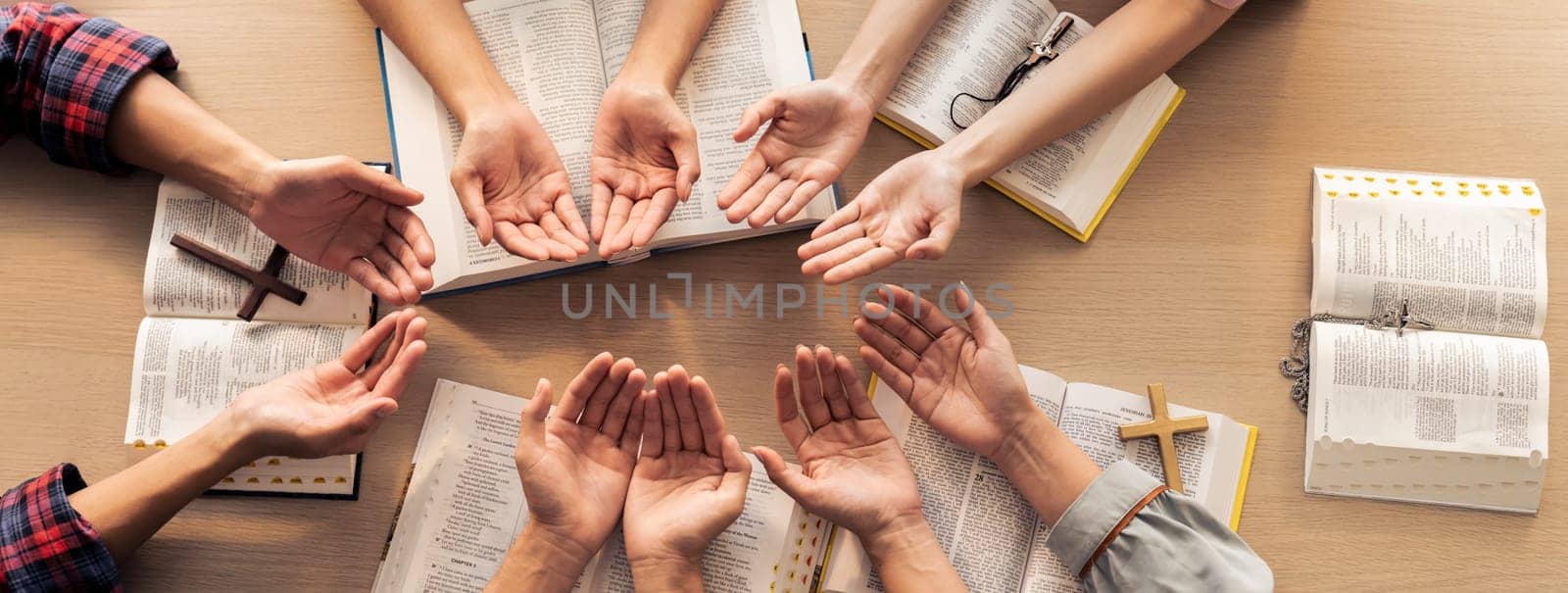 Cropped image of diversity people hand praying together at wooden church on bible book. Group of believer hold hand together faithfully. Concept of hope, religion, faith, god blessing. Burgeoning.