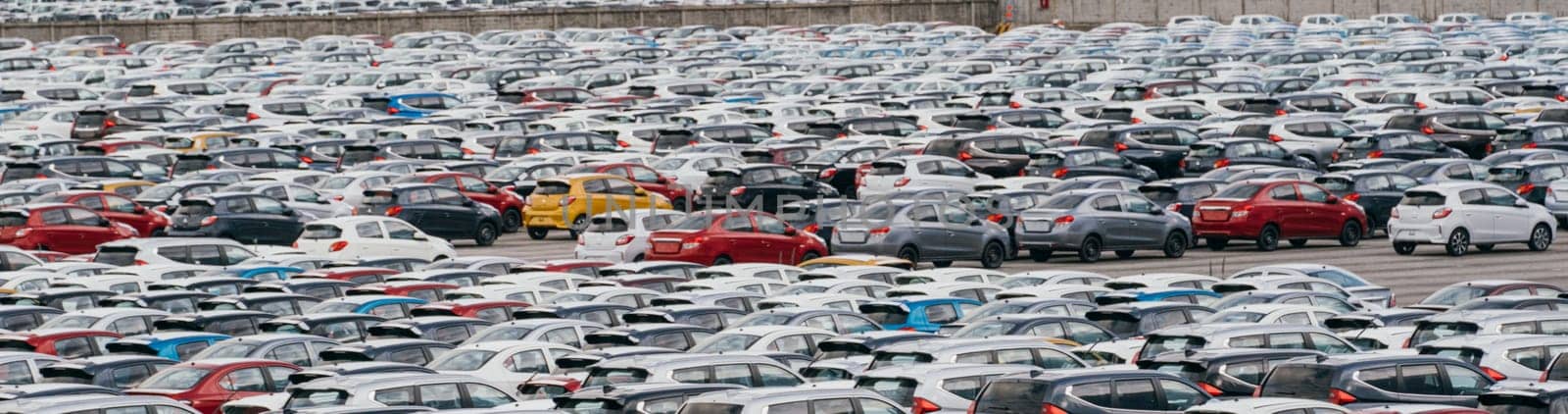 Lamchabang, Thailand - July 02, 2023 On a sunny day at a car factory, rows of new cars are parked in a distribution centera top view of the bustling parking lot is a testament to modern industry.