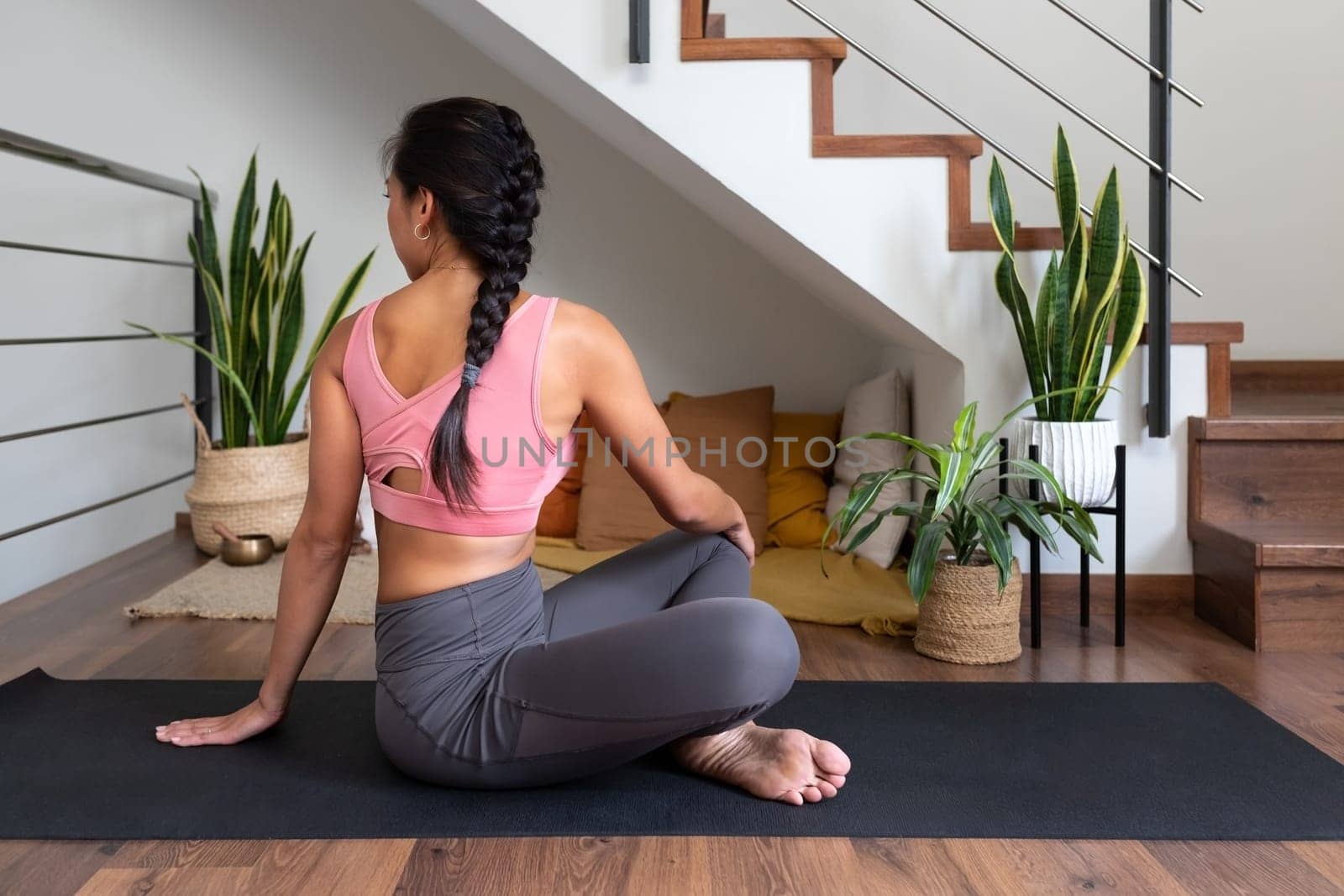 Young woman doing seated twist yoga pose at home. Active and healthy lifestyle.