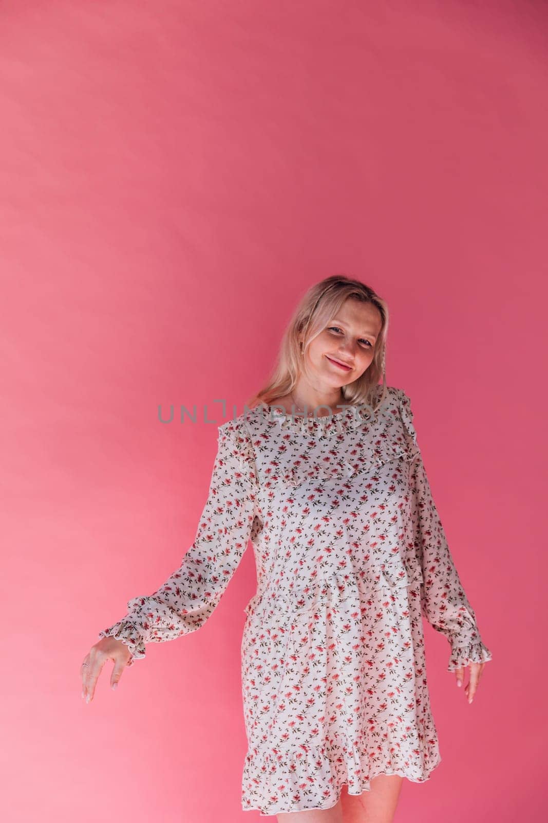 Woman smiling and dancing to music on pink background by Simakov