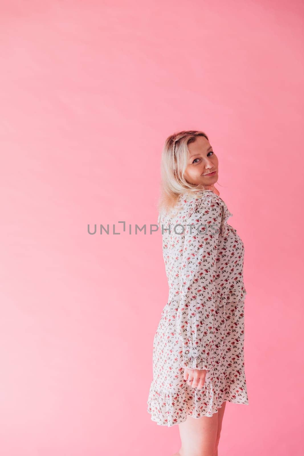 Woman smiling and dancing to music on pink background by Simakov