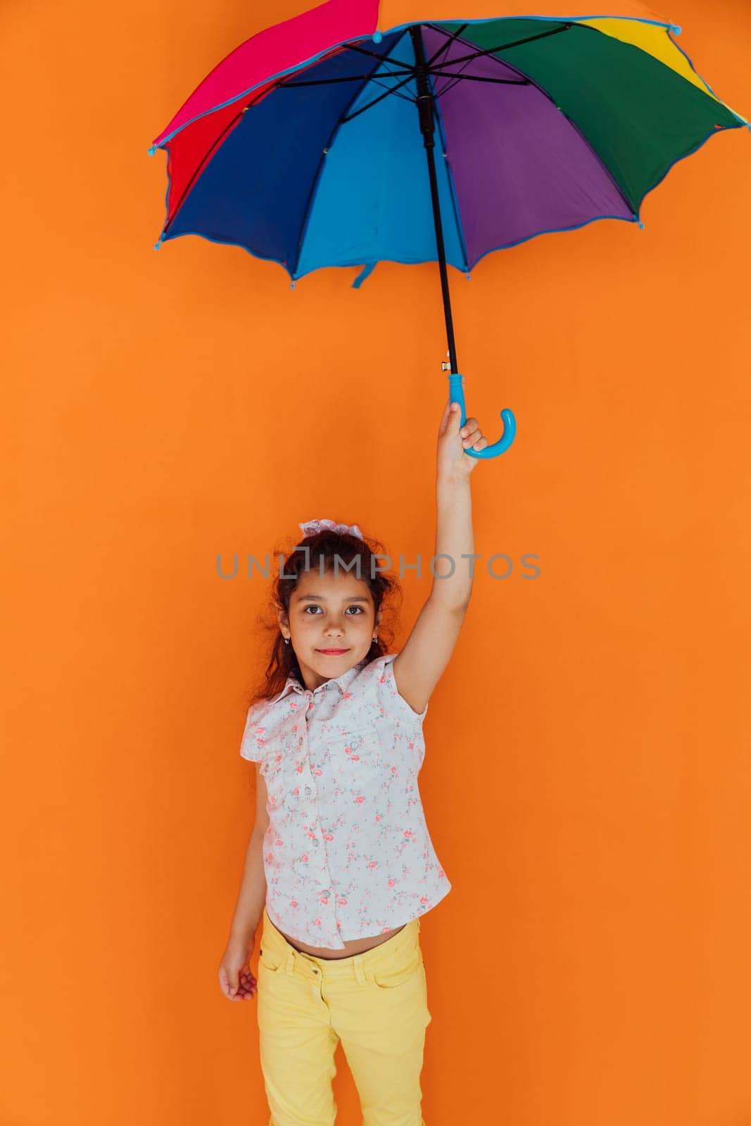 Little girl with multicolored zant from rain on orvange background