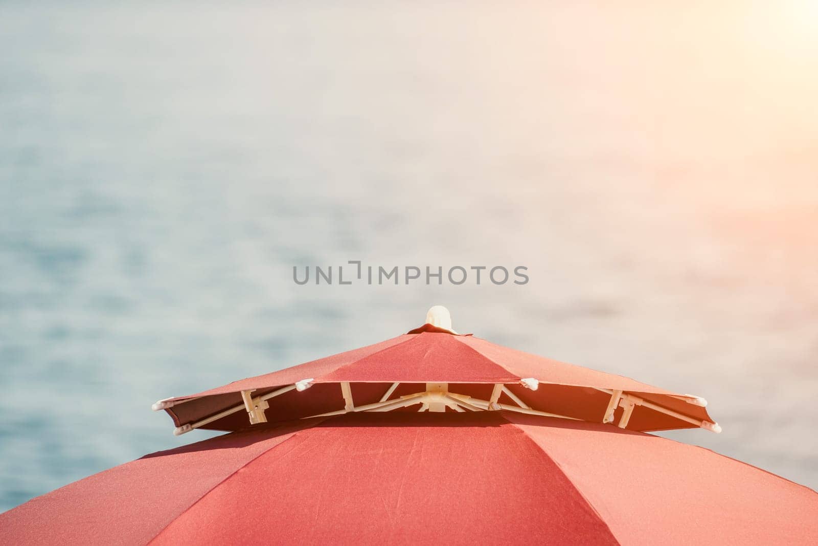 Red Beach Umbrella on the Background of the Blue Sea Ocean. Beach Landscape. Summer travel and holidays concept