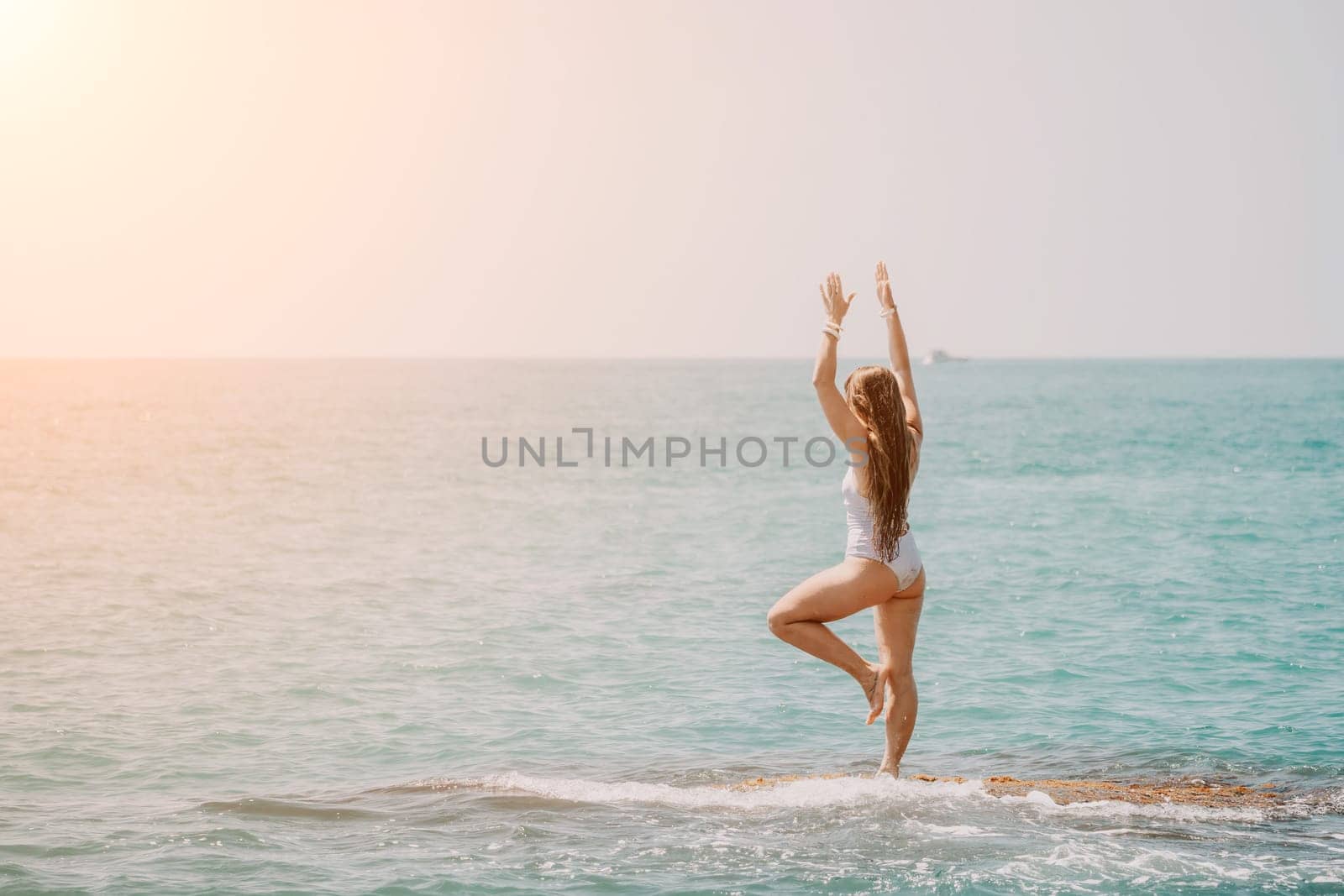 Woman sea yoga. Back view of free calm happy satisfied woman with long hair standing on top rock with yoga position against of sky by the sea. Healthy lifestyle outdoors in nature, fitness concept.