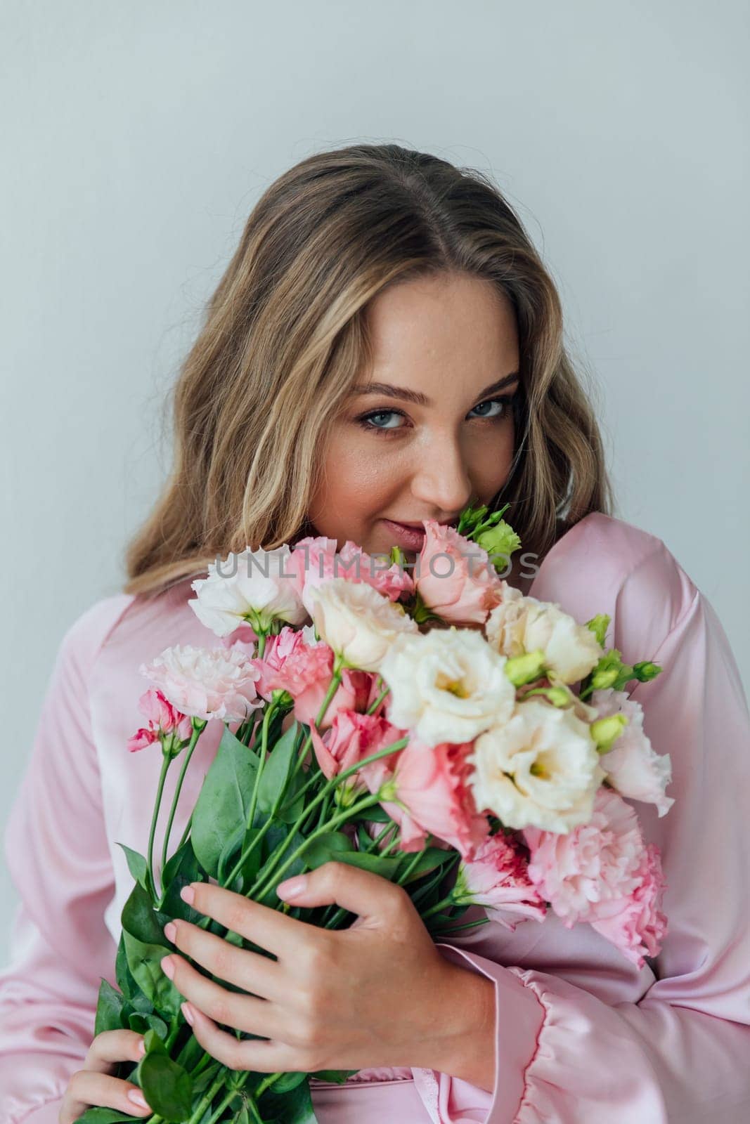 portrait of blonde woman with eustoma flowers on a white background