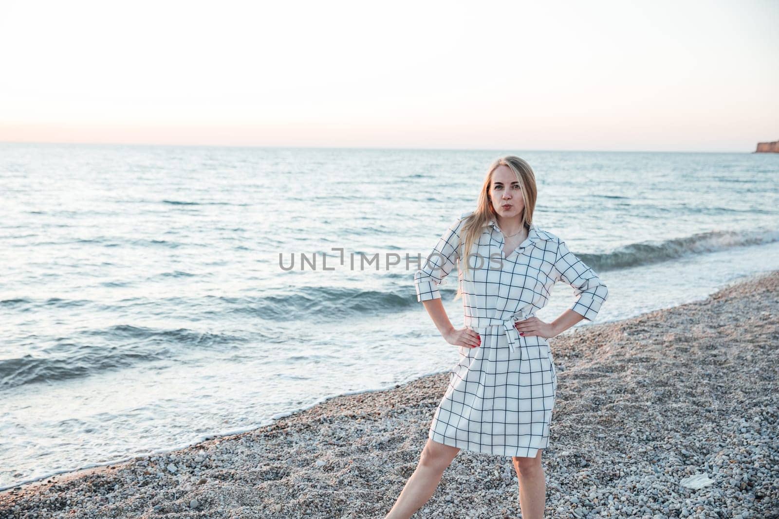 beautiful blonde woman in a summer dress on the beach by the sea
