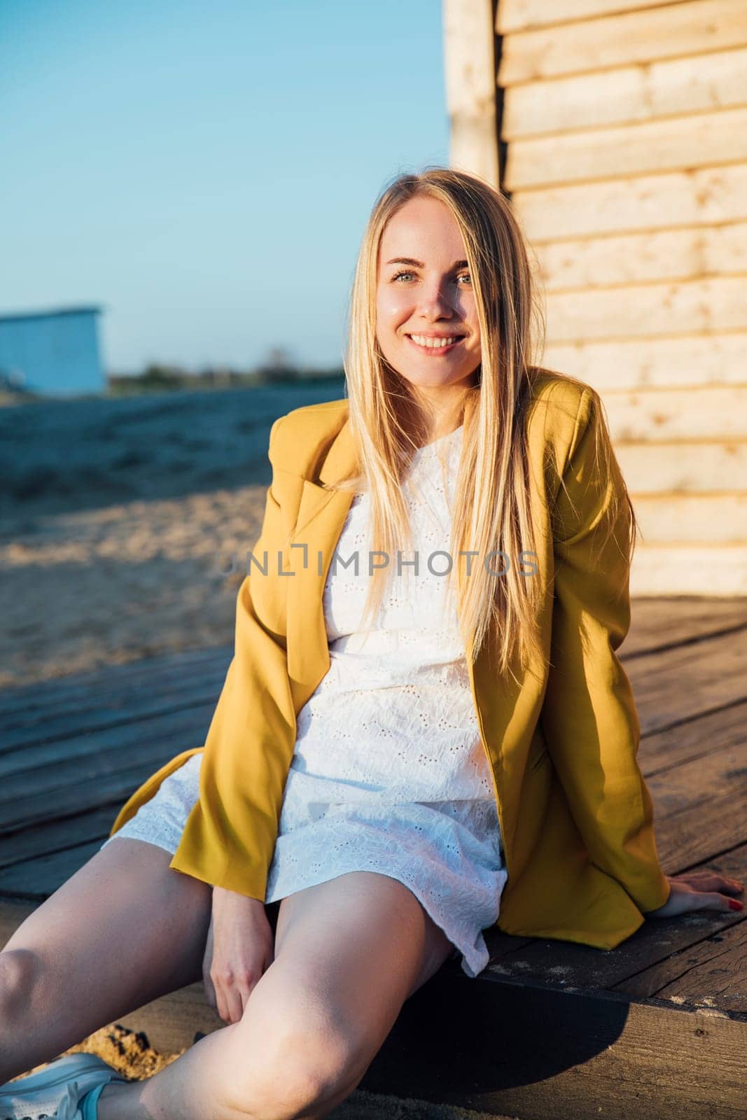 beautiful blonde woman in a light summer dress and yellow jacket
