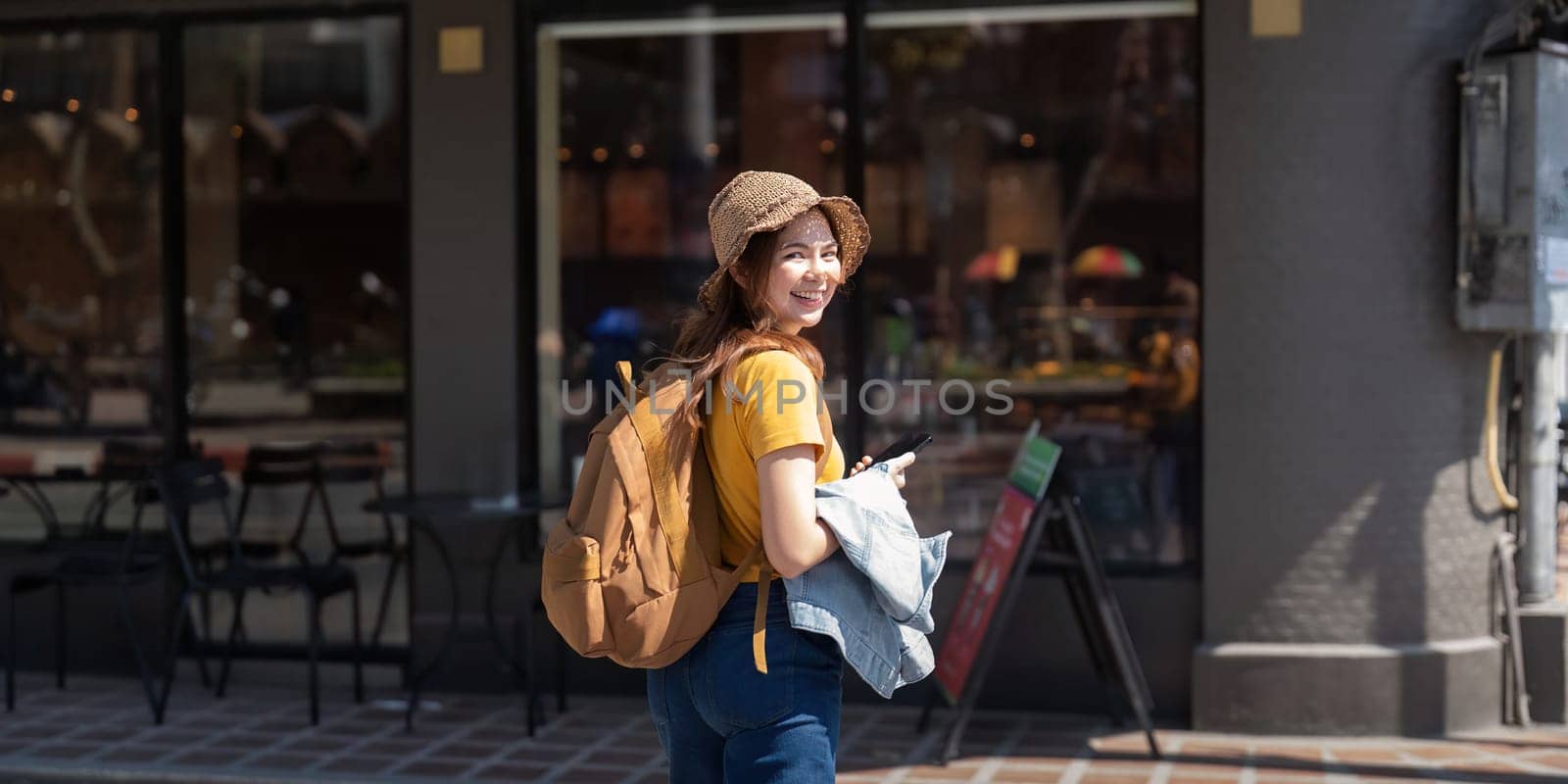 Asia woman tourist walking and using a smart phone in the street in a sunny summer.