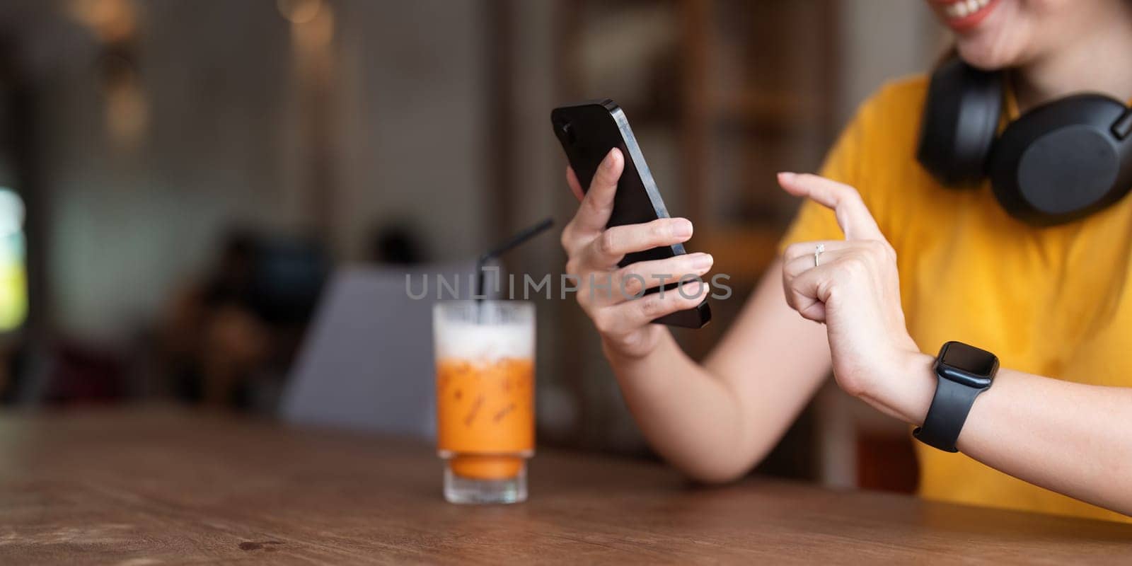 Young woman wearing headphones listening to music on her smartphone relax in cafe.