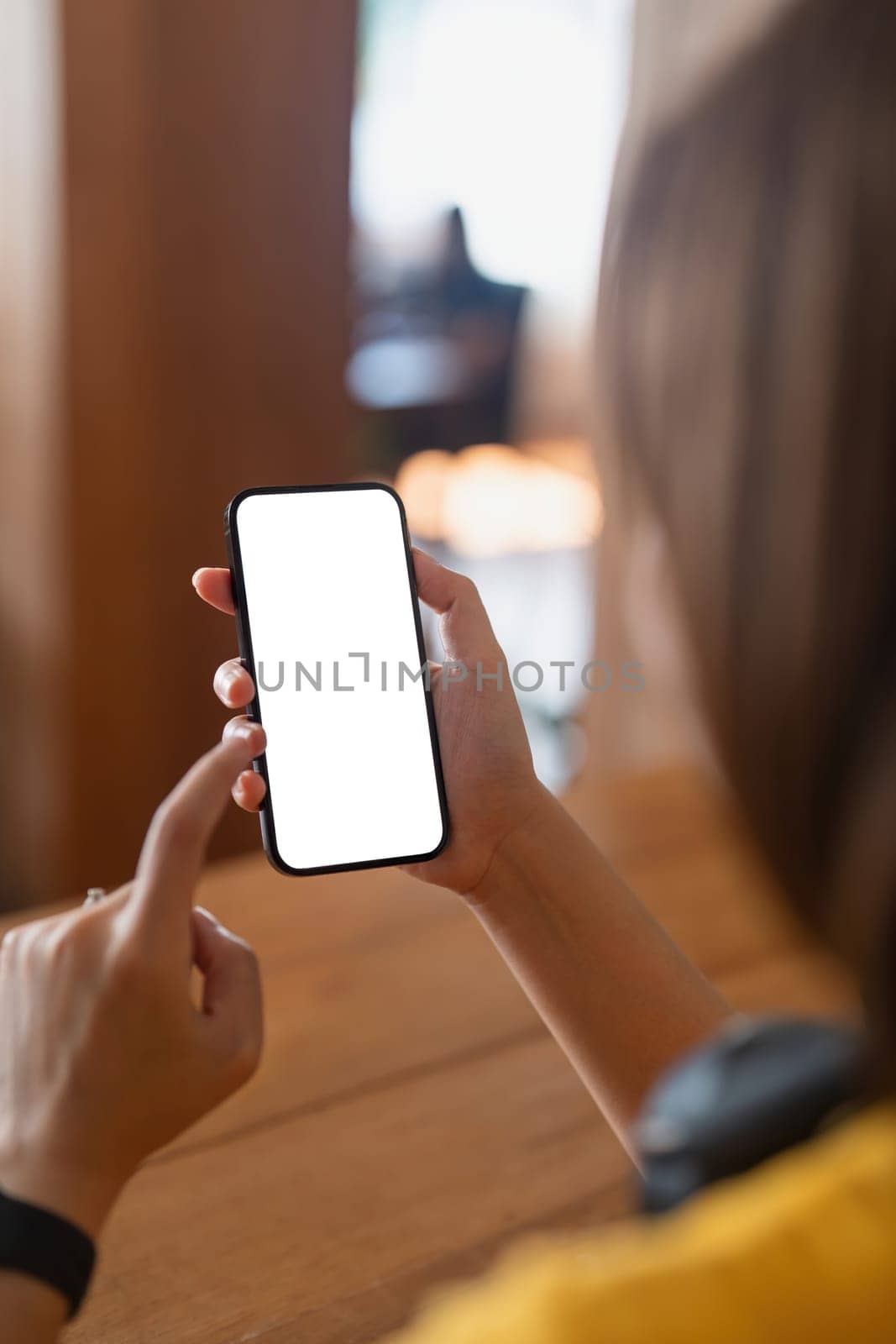 Woman hand holding using mockup mobile phone at coffee shop with copy space, white blank screen for text, mobile app design and advertising, online marketing by nateemee