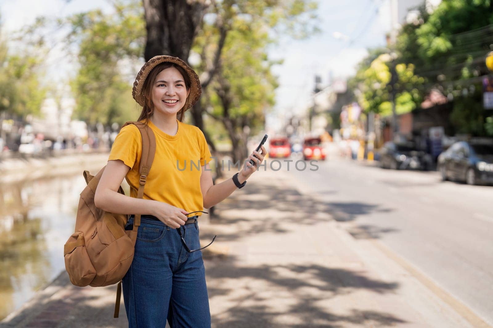 Asia woman tourist walking and using a smart phone in the street in a sunny summer.