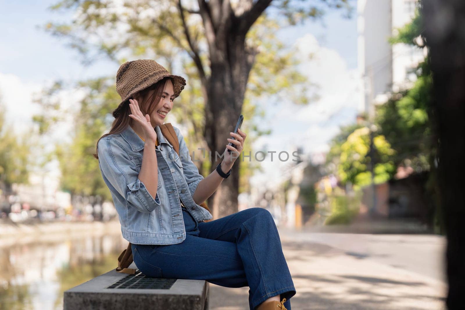 Asian woman in city street using mobile phone while taking selfie.
