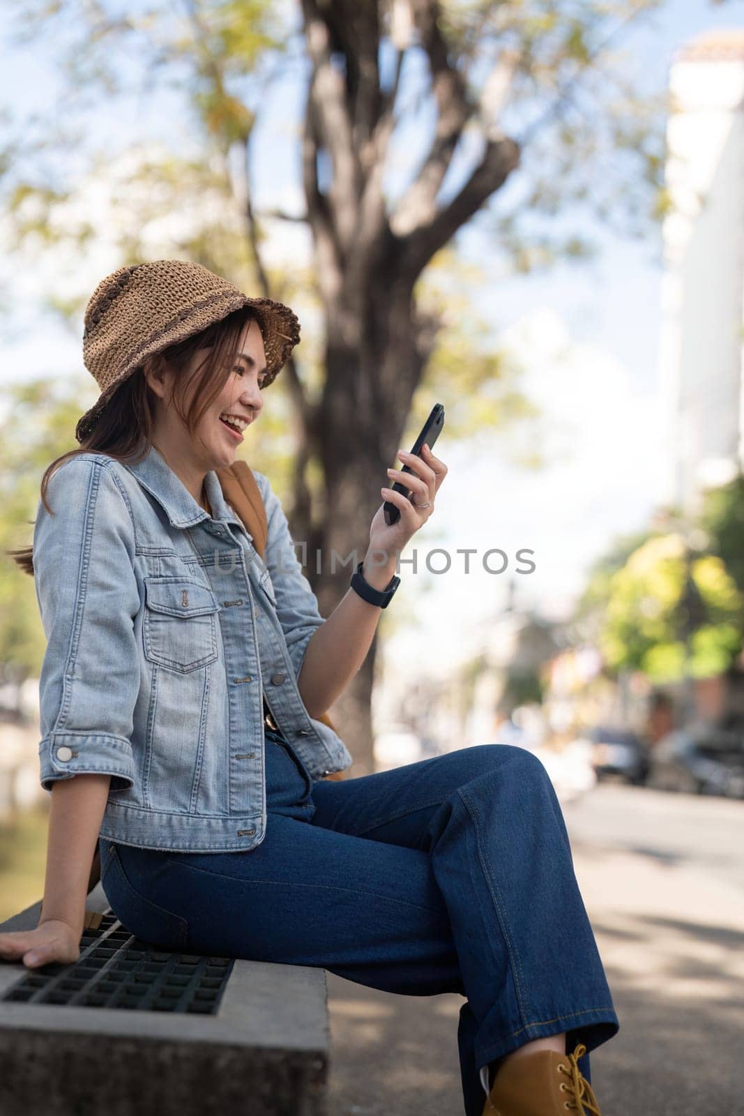 Young beautiful smiling asian woman tourist in city street using mobile phone check direction or use social media.