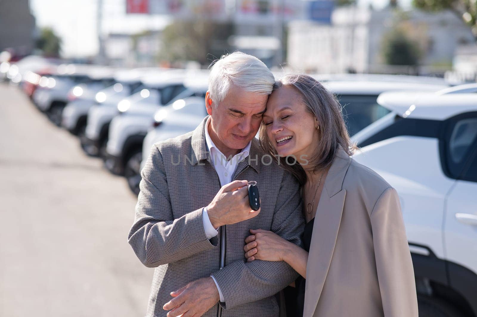 Mature Caucasian couple standing by a car outdoors. Elderly man holding car keys. by mrwed54