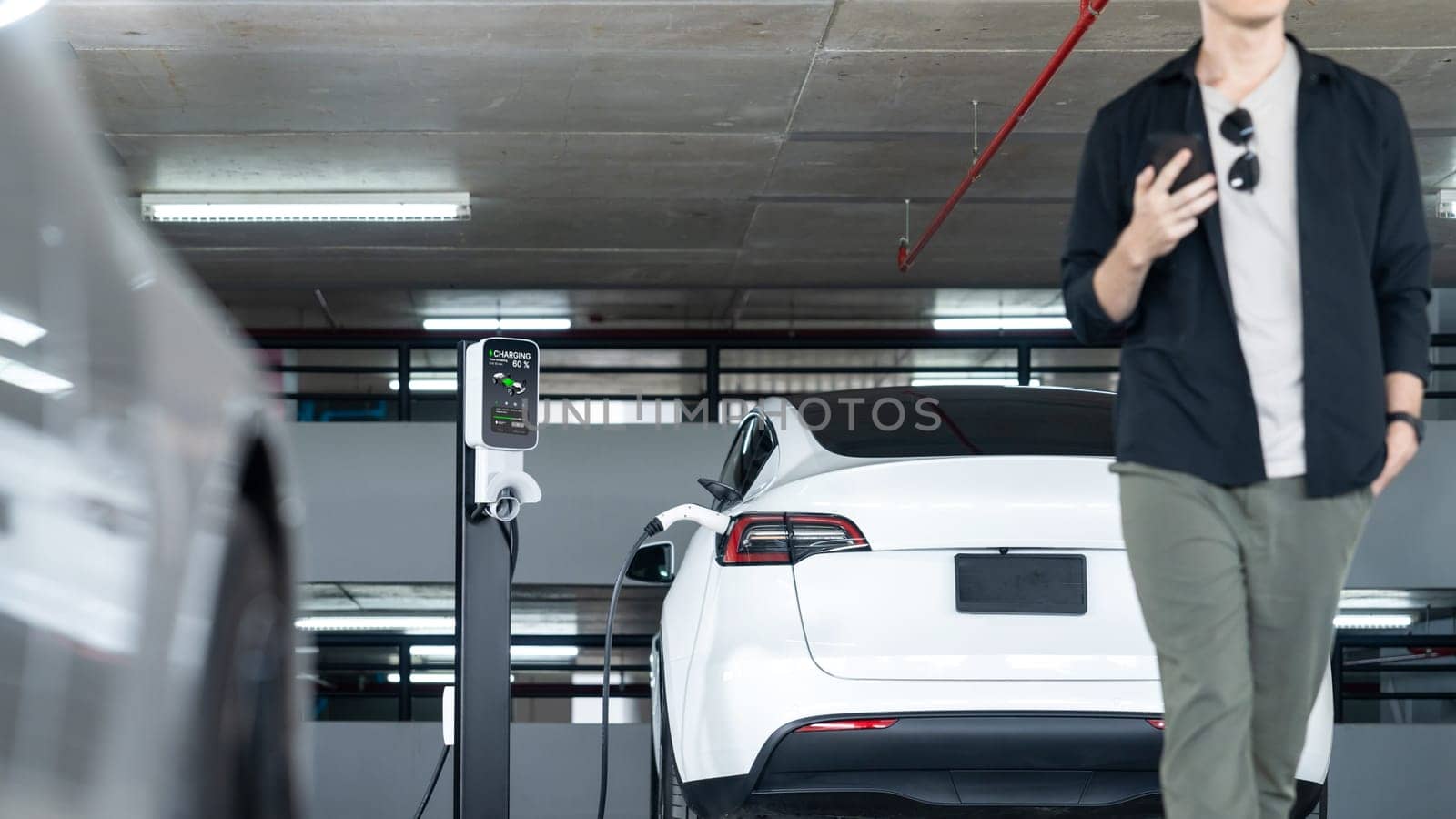 Young man travel with EV electric car to shopping center parking lot innards by biancoblue